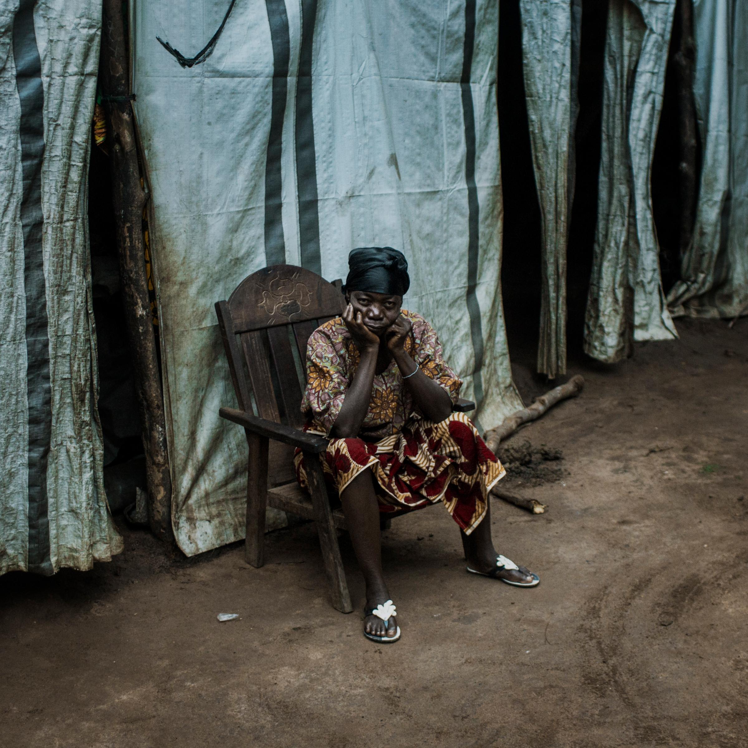 A displaced woman sits by her tent made by plastic sheeting in a camp for internally displaced people in Kaga Bandoro, Central African Republic, July 30, 2015.