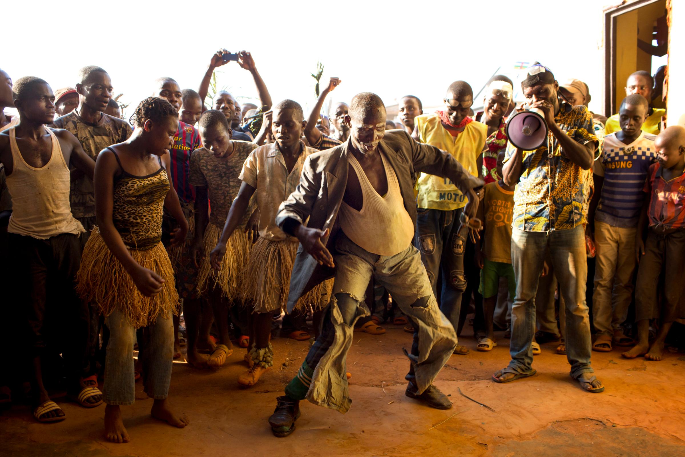 A man disguised as pregnant woman dances to welcome candidate Anicet Georges Dologuelé, who is running for president, at the aerodome in Mobaye, Central African Republic, Dec. 20, 2015.