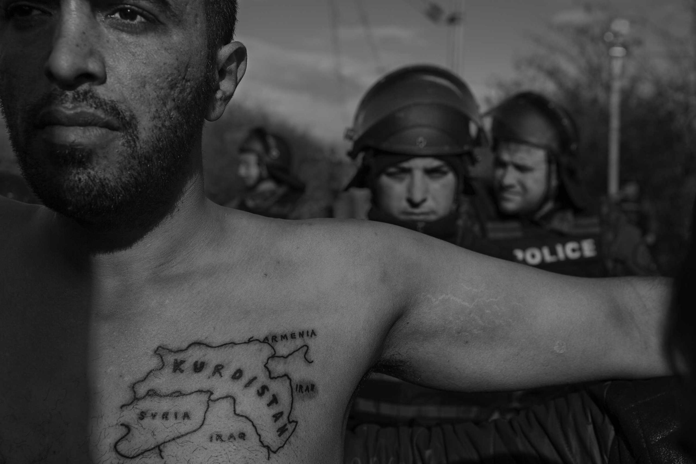 A man spreads his arms in a  bid to defuse tensions between asylum seekers and police at a demonstration at the Macedonian border.