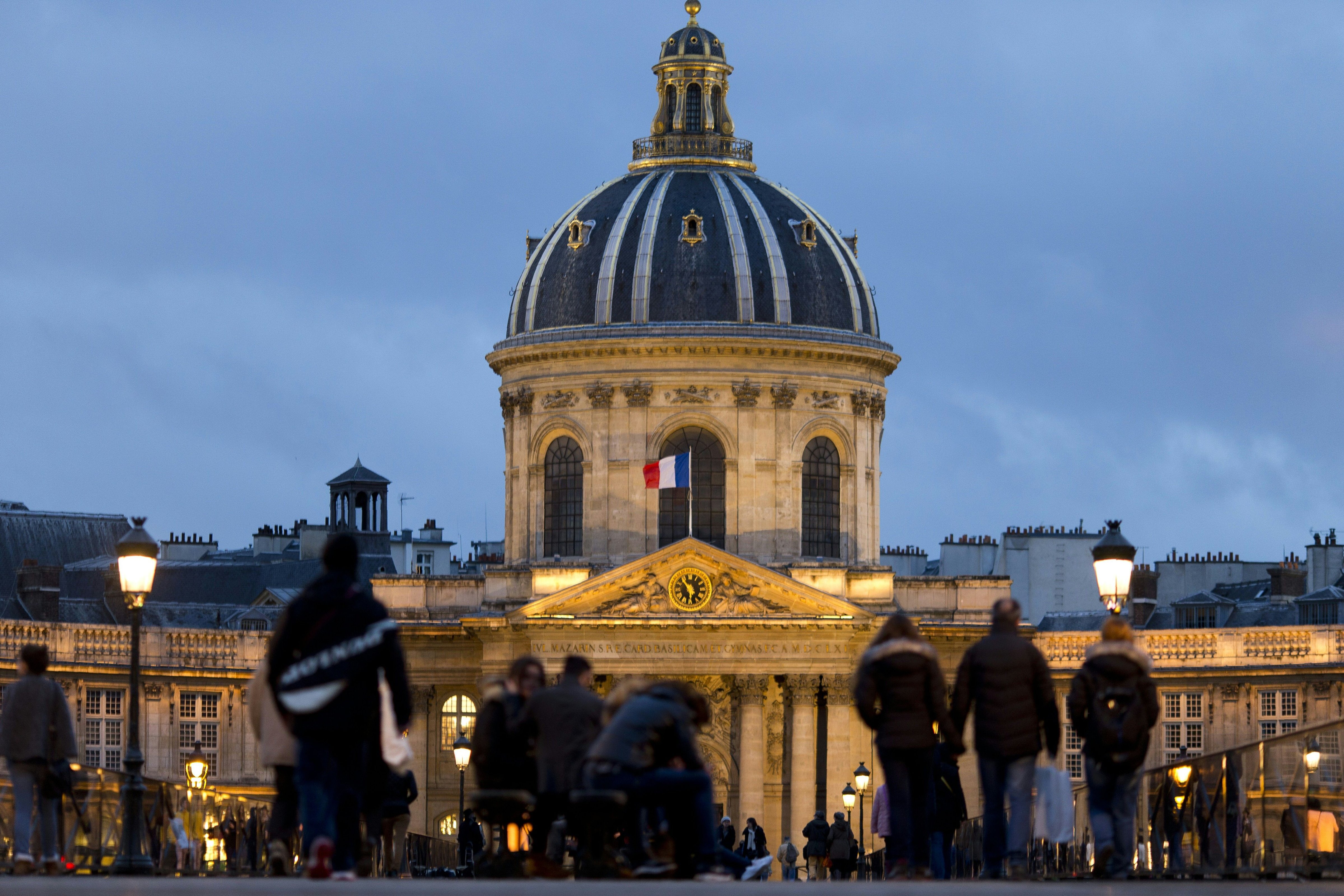 People walk on a bridge in front of the Institut de France building which houses the Academie Francaise in Paris on Feb. 1. (KENZO TRIBOUILLARD—AFP/Getty Images)