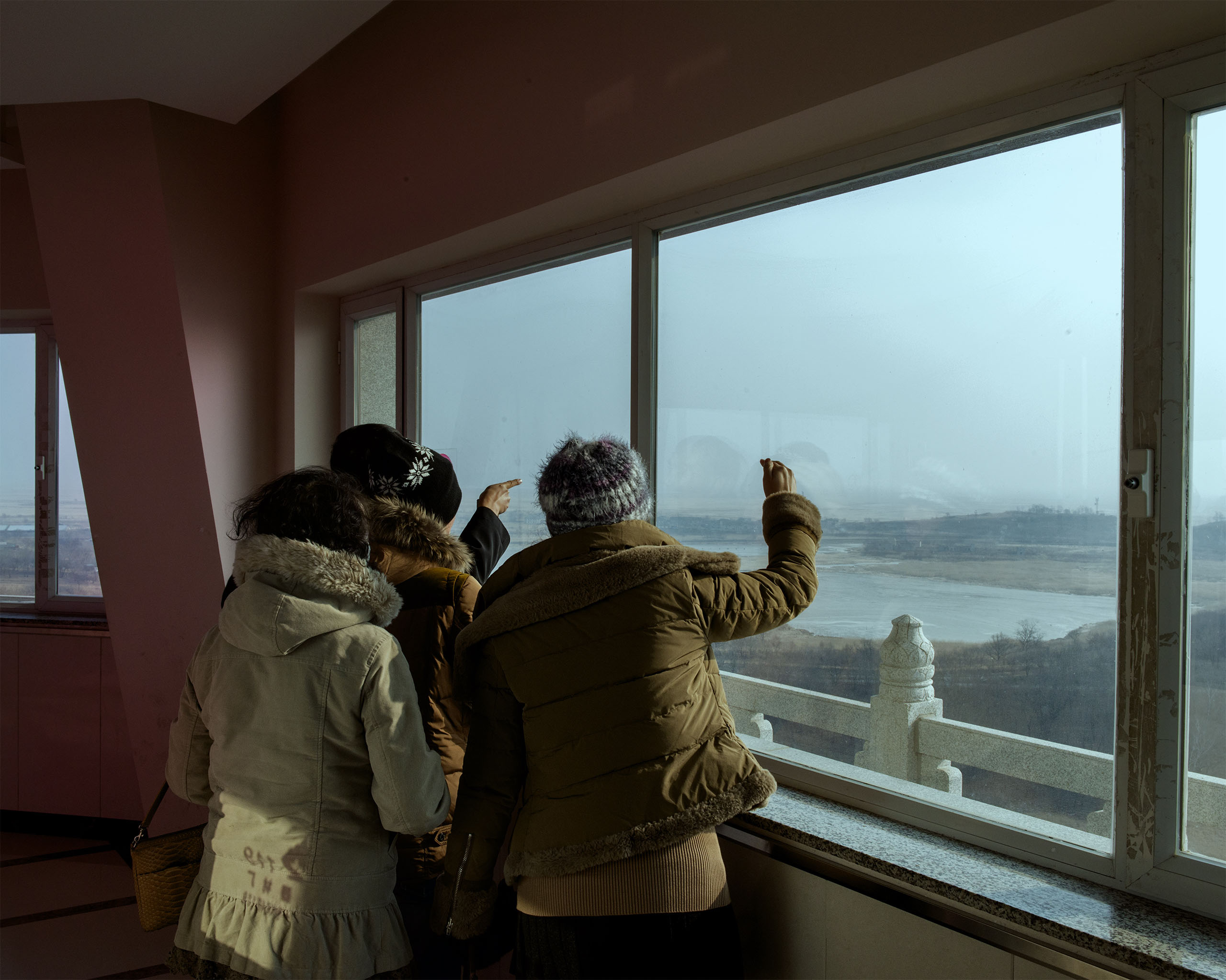 South Korean tourists point in Hunchun, China, point toward North Korea across the Tumen River. The Russian border lies to their left.