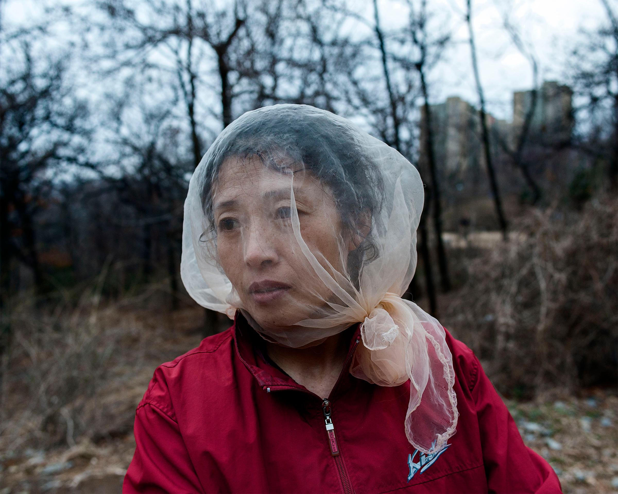A woman in Dandong, China covers her face with a piece of cloth to protect from mosquitos. In China's border cities, there is a normality to daily life which stands in contrast to the deprivation across the border.