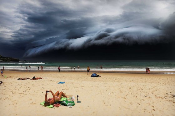 Nature, 1st prize singles. A massive 'cloud tsunami' looms over Sydney as a sunbather reads, oblivious to the approaching cloud on Bondi Beach, Sydney, Australia on Nov. 6, 2015.