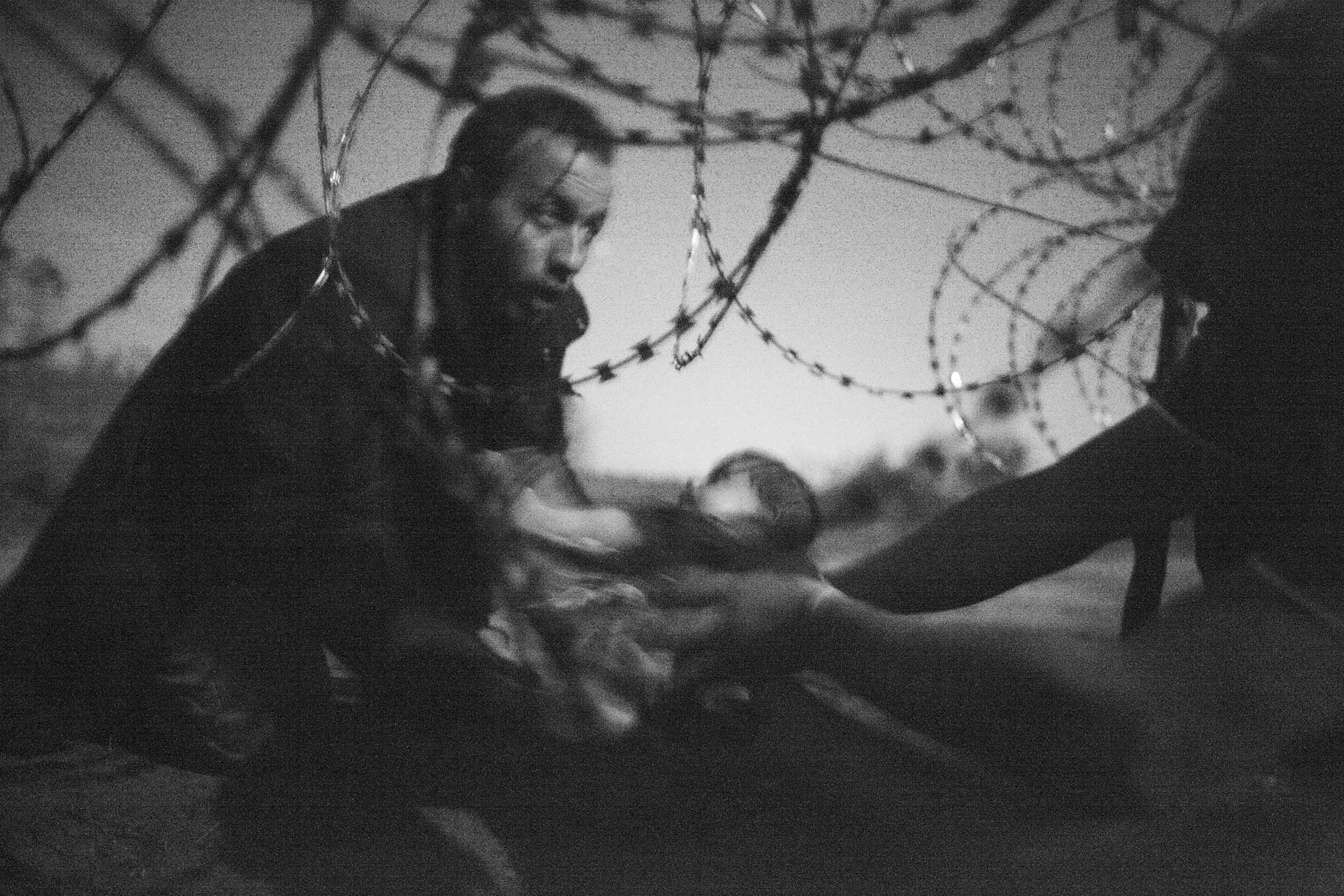 <b>Spot News, 1st prize singles and World Press Photo of the Year.</b> A man passes a baby through the fence at the Hungarian-Serbian border in Röszke, Hungary, Aug. 28, 2015. (Warren Richardson)