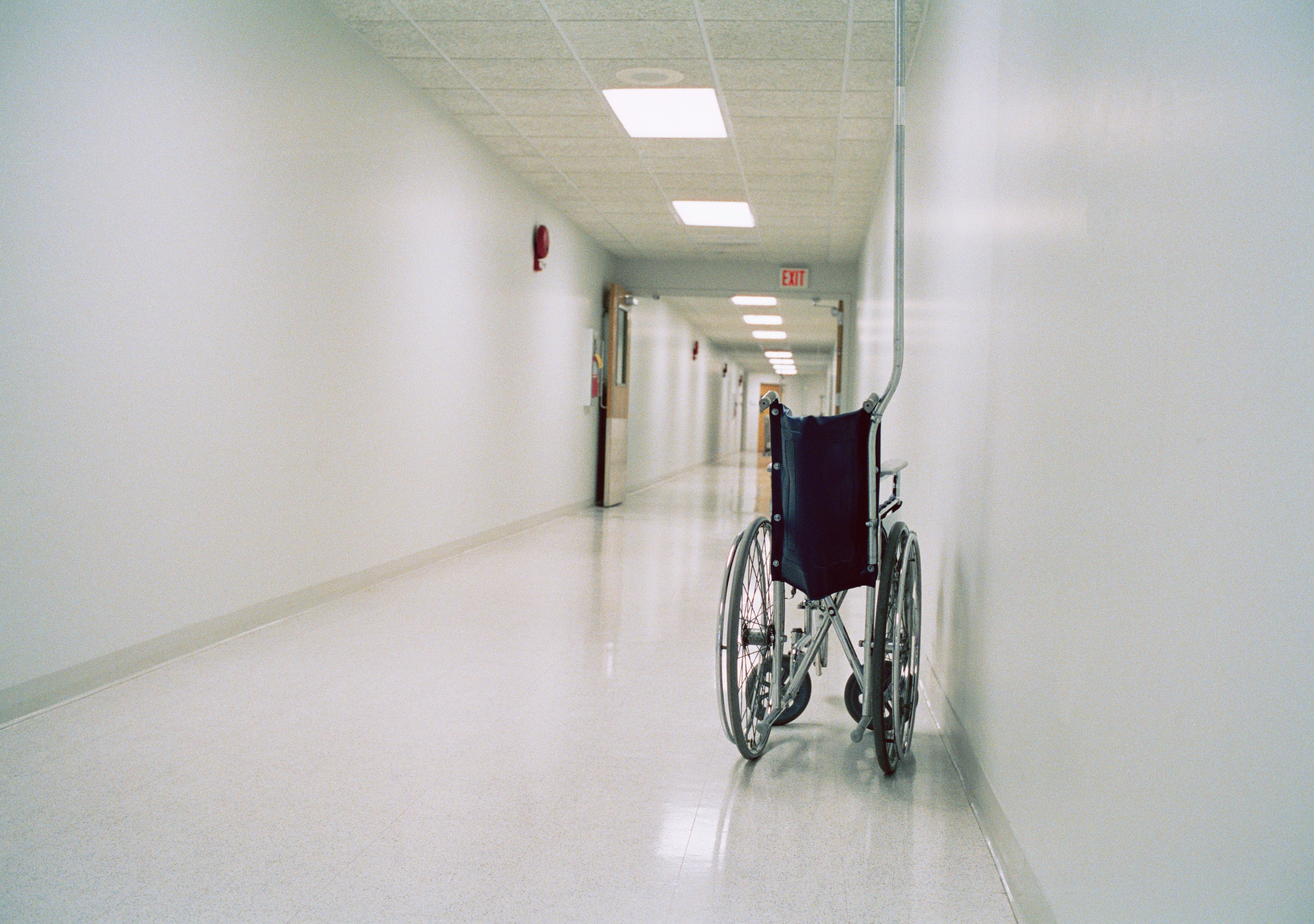 Collapsible wheelchair in empty corridor of hospital (Reza Estakhrian—Getty Images)
