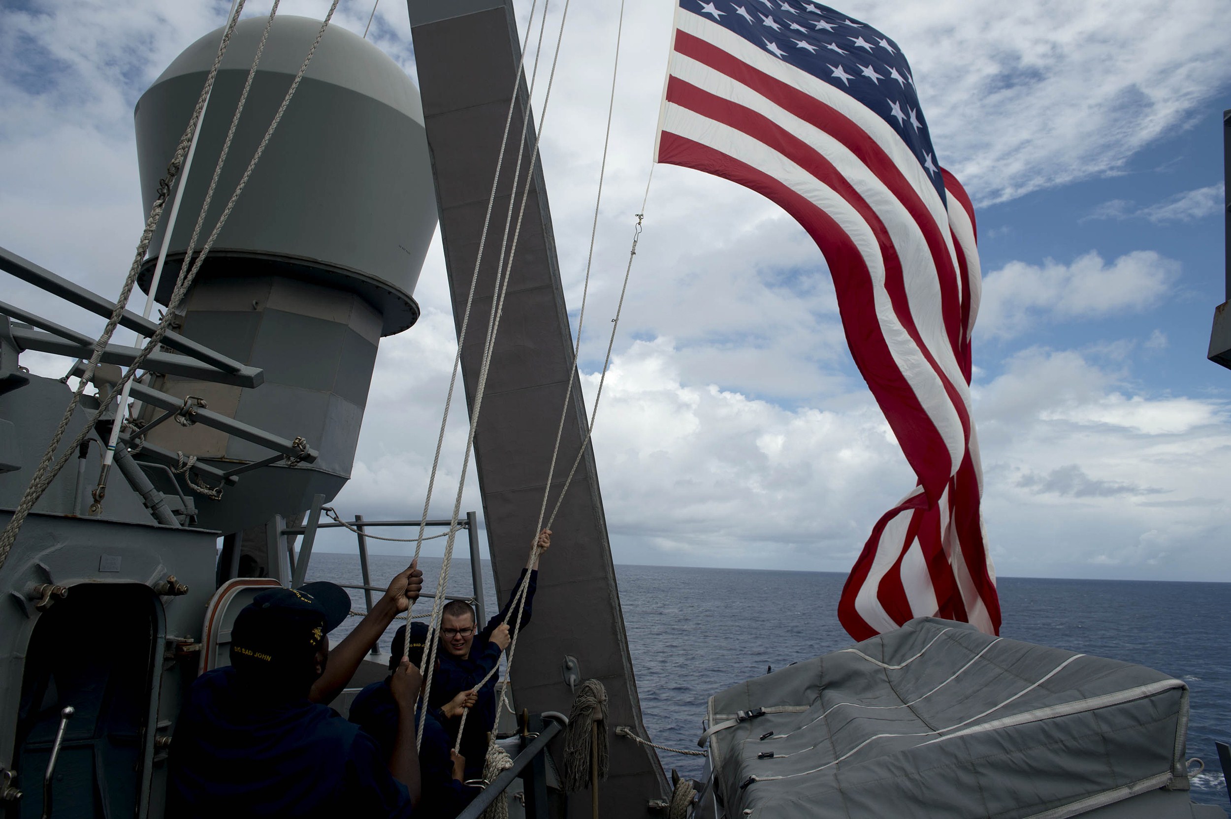 U.S. Navy personnel aboard the U.S.S. <i>John S. McCain</i> raise their country's flag during a bilateral maritime exercise with the Philippine navy in the South China Sea near waters claimed by Beijing on June 28, 2014 (Noel Celis—AFP/Getty Images)