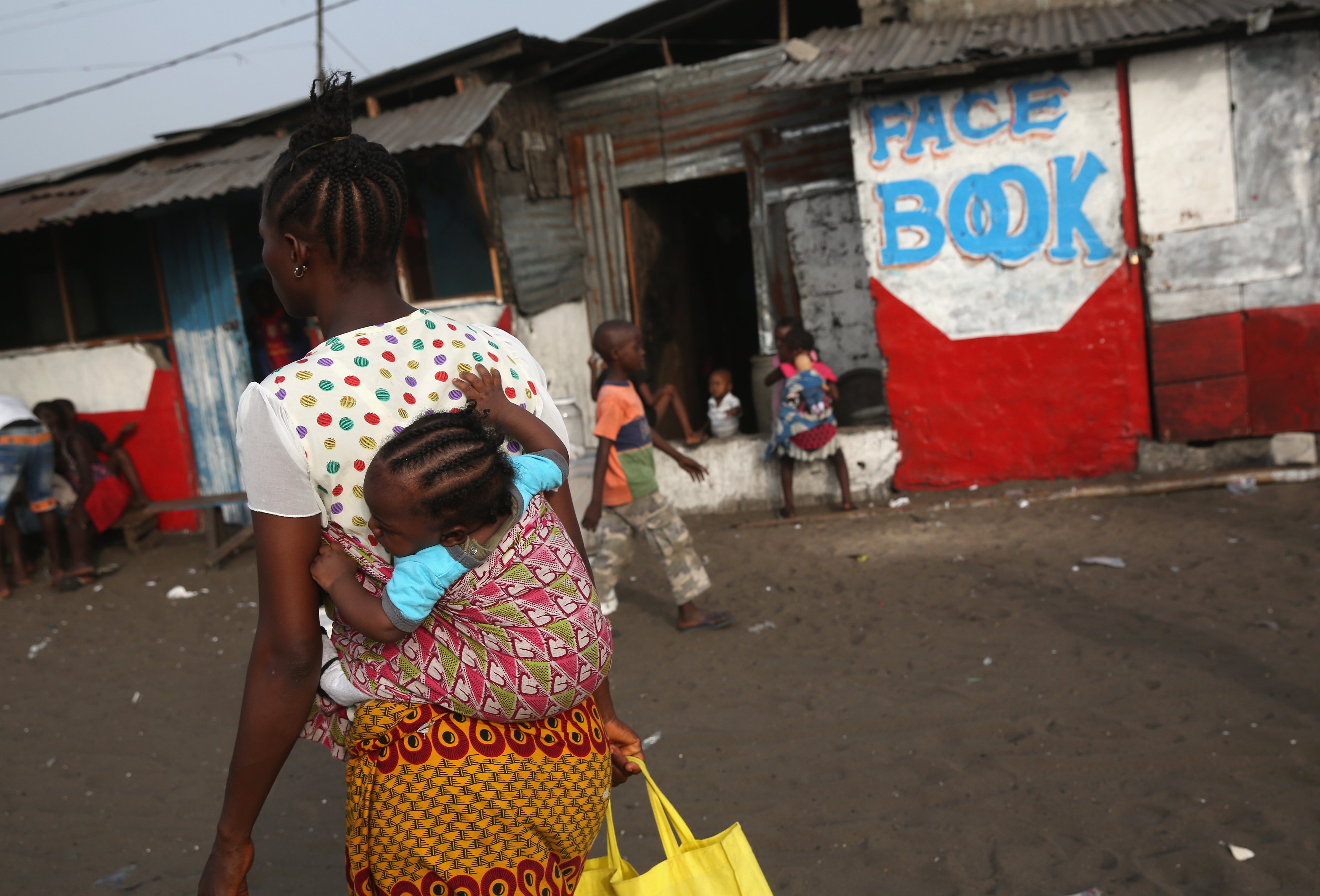 A woman and her child pass by an Internet caf&eacute; in the West Point slum on Feb. 9, 2016, in Monrovia, Liberia (John Moore—Getty Images)