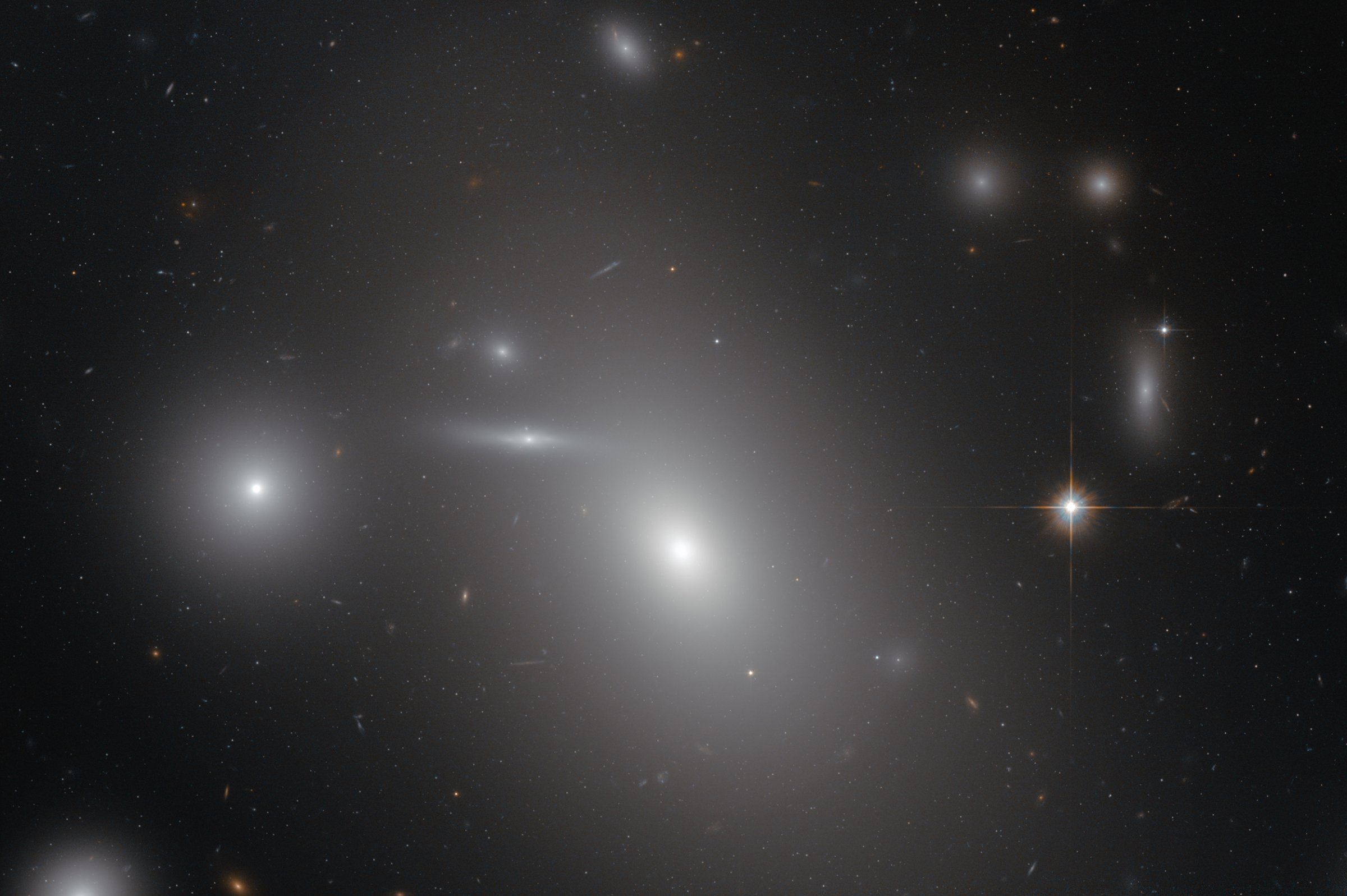 The elliptical galaxy NGC 4889 in front of hundreds of background galaxies, and deeply embedded within the Coma galaxy cluster. Hidden from human eyes, is a gigantic supermassive black hole at the centre of the galaxy.