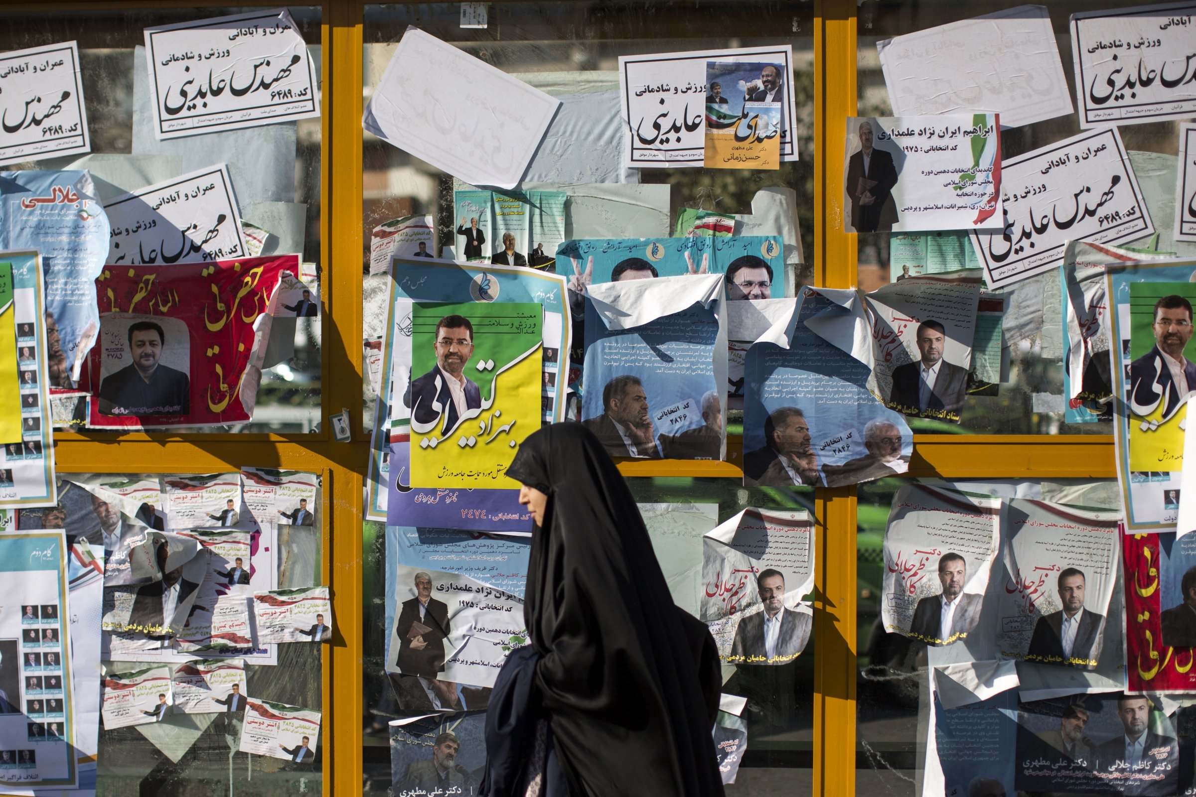 An Iranian woman walks past electoral posters for upcoming parliamentary elections in downtown Tehran on Feb. 25, 2016.