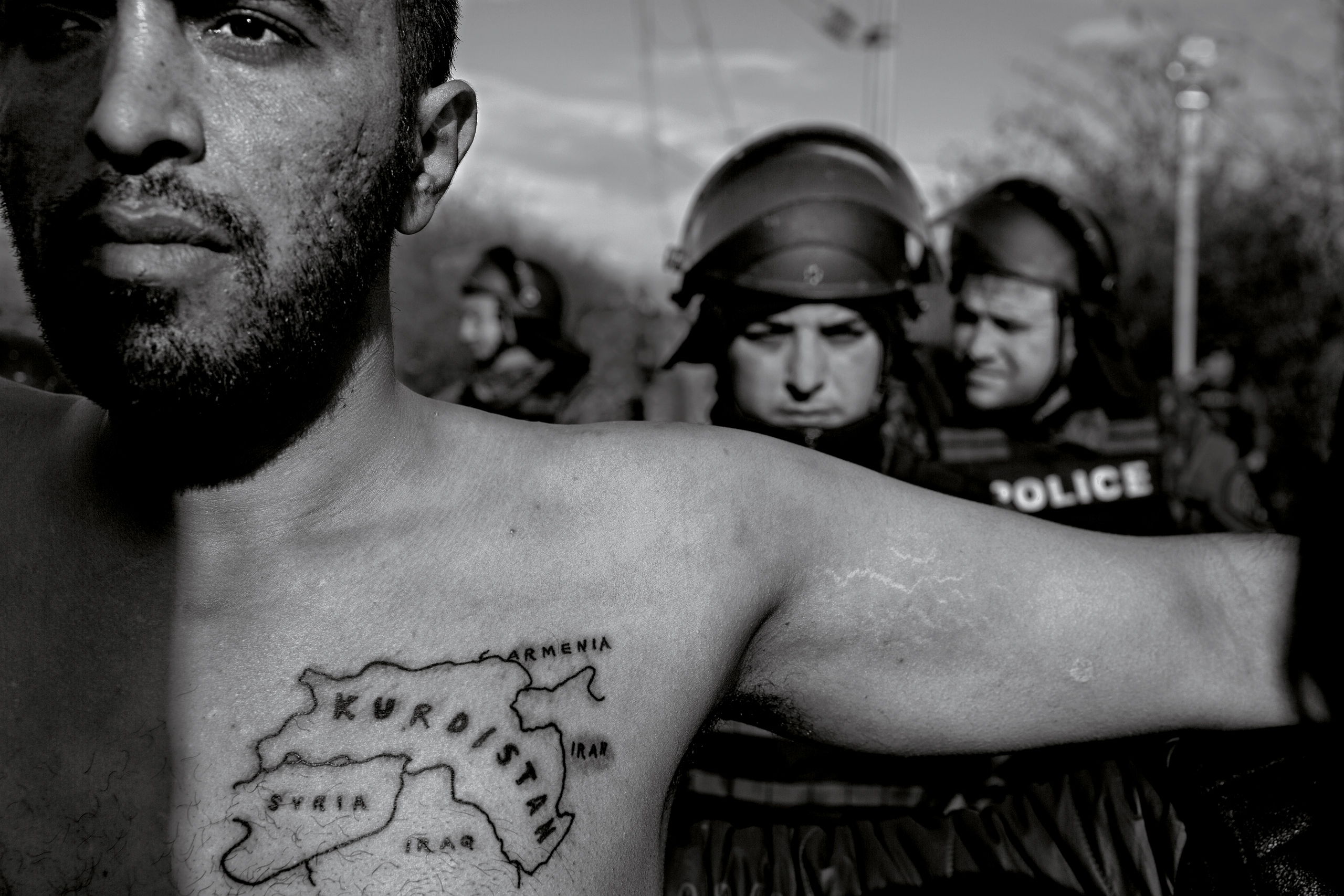 A man spreads his arms in a bid to defuse tension between migrants and police (James Nachtwey for TIME)