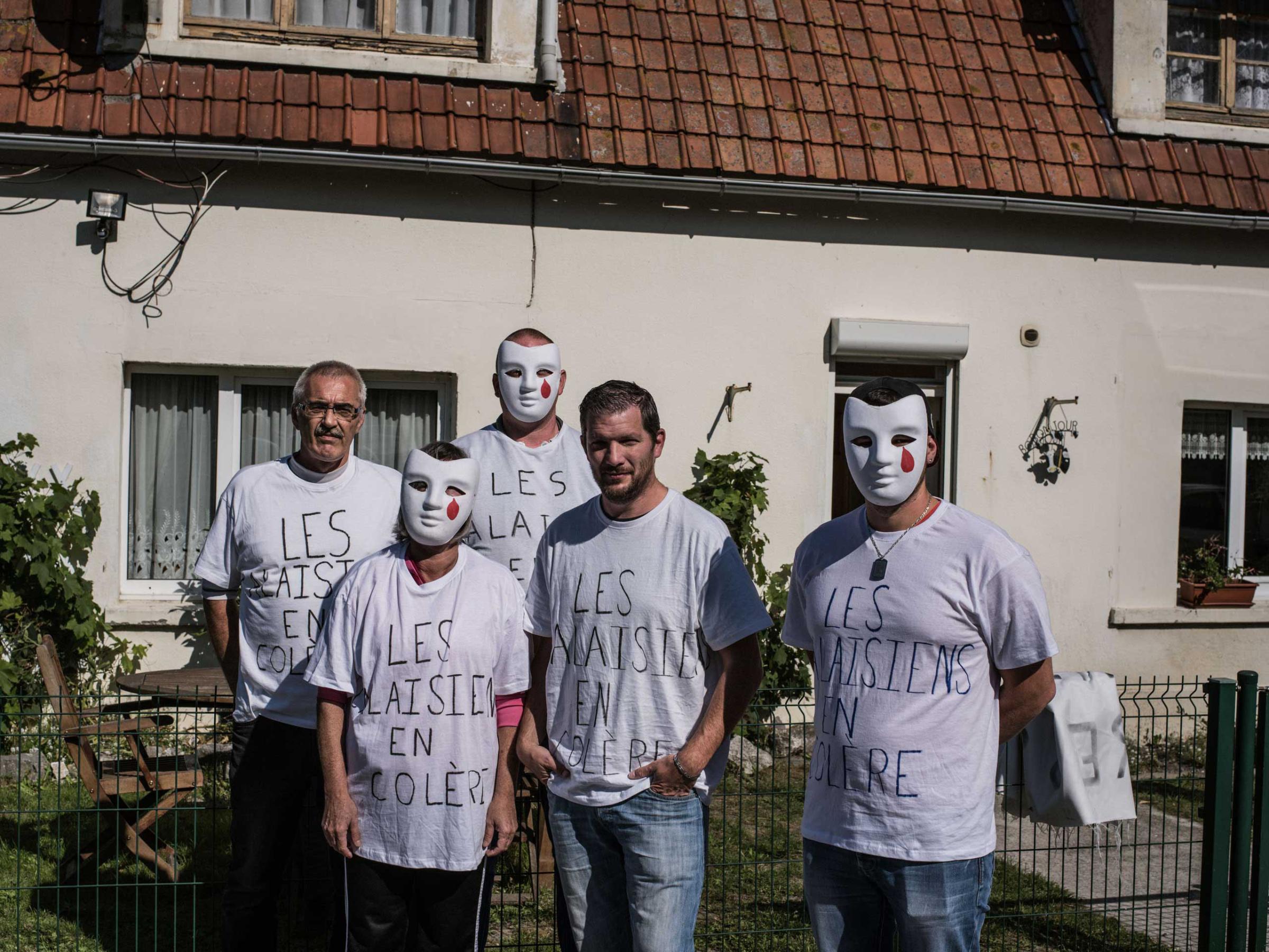 A group of neighbors wear tee-shirts proclaiming  "Angry Calaisiens," while protesting the migrant camp known as the "jungle," Sept. 11, 2015.