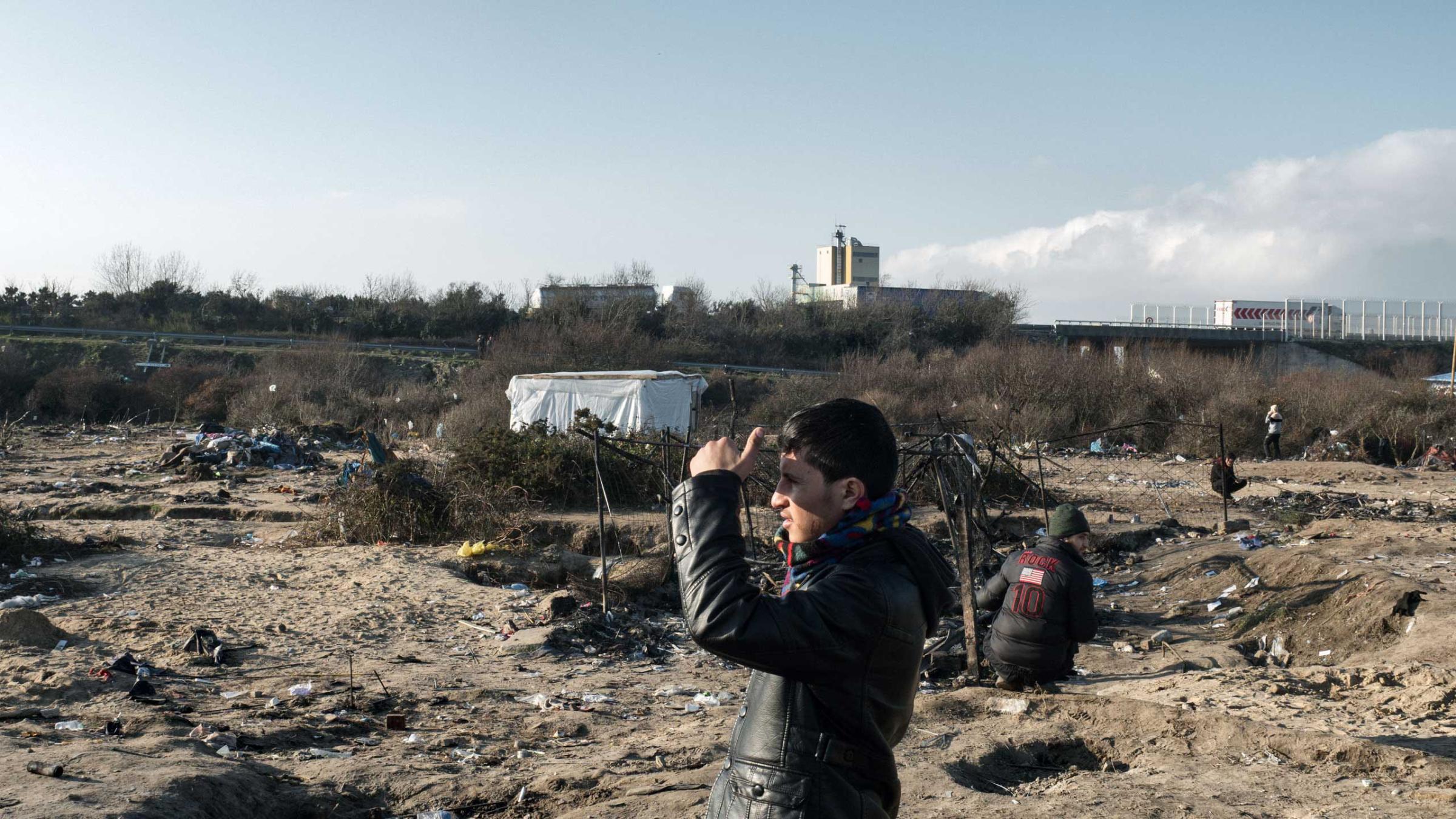 A young man looks out in an area in Calais, France that is being cleared for new housing containers, Jan. 20, 2016.