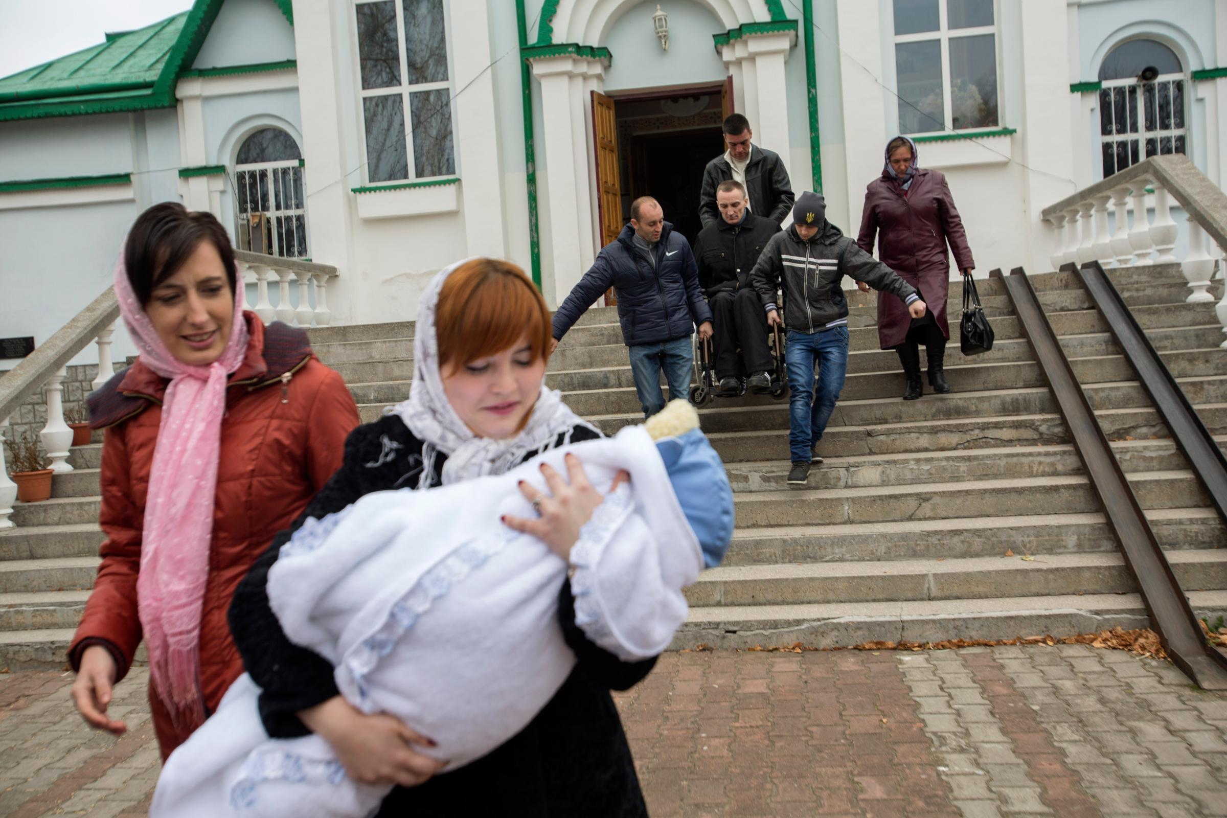 Honcharovsky is assisted down a set of stairs after his son's christening at a church in Teofipol, Ukraine, Nov. 16, 2014. Proper infrastructure for the physically disabled barely exists in some Ukrainian cities, towns and villages.