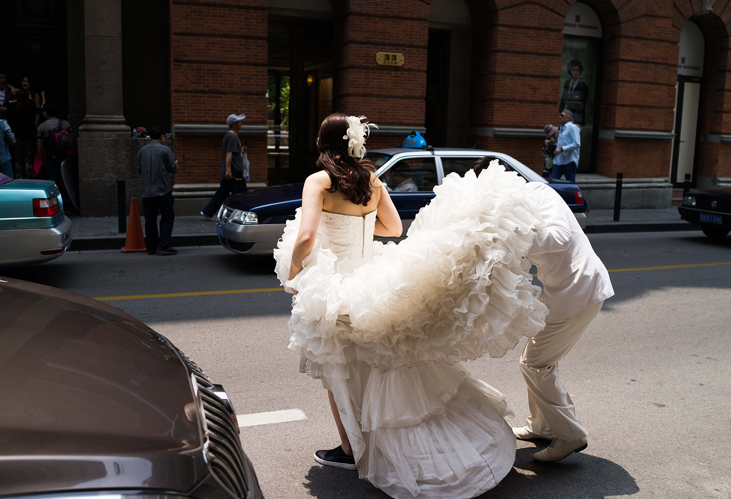 A bride-to-be has her dress adjusted during a photo shoot in Shanghai in May 2013.