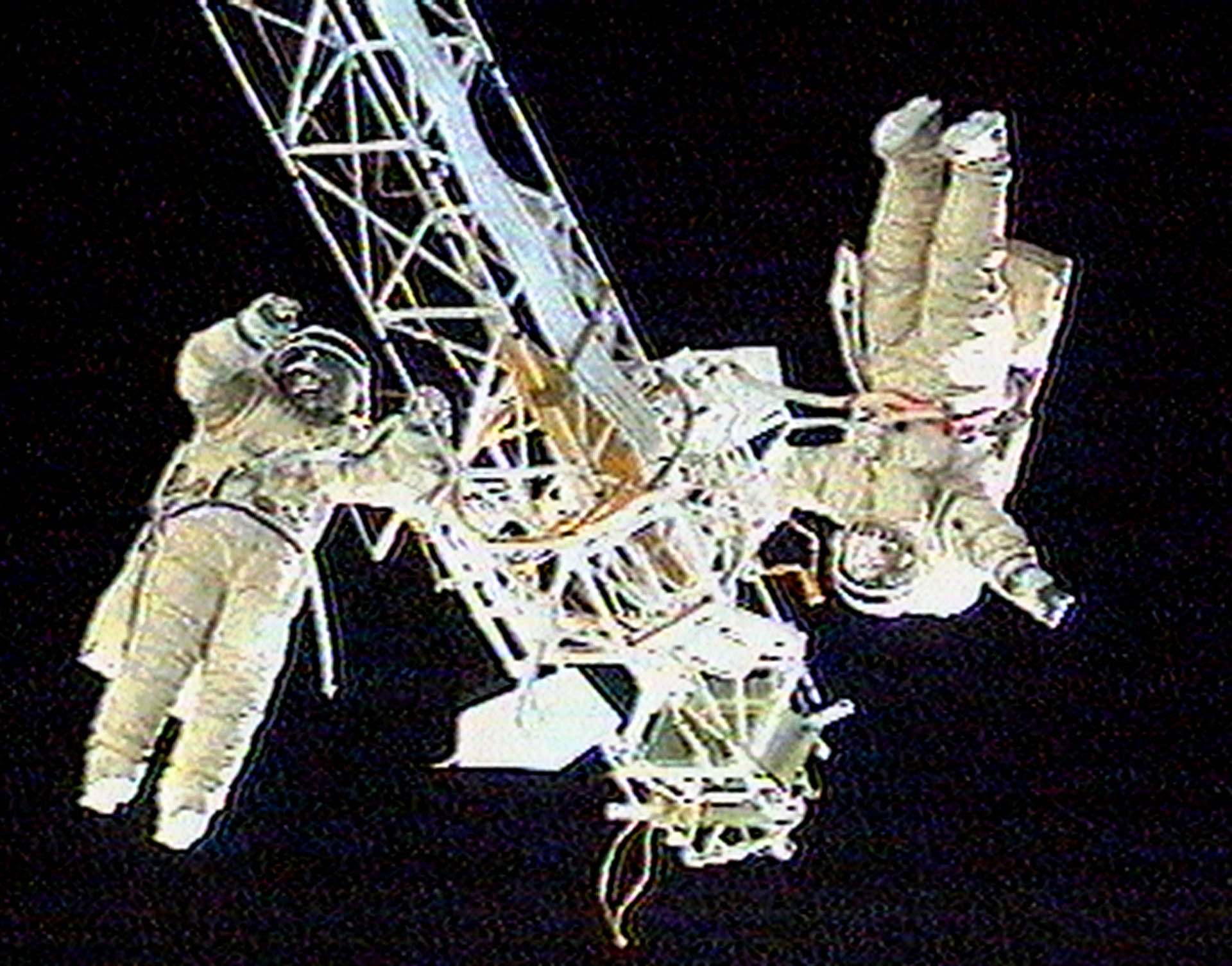 Two Russian cosmonauts hold on to a 14-meter girder outside the aging Mir station discarding a faulty thruster engine on April 11, 1998.