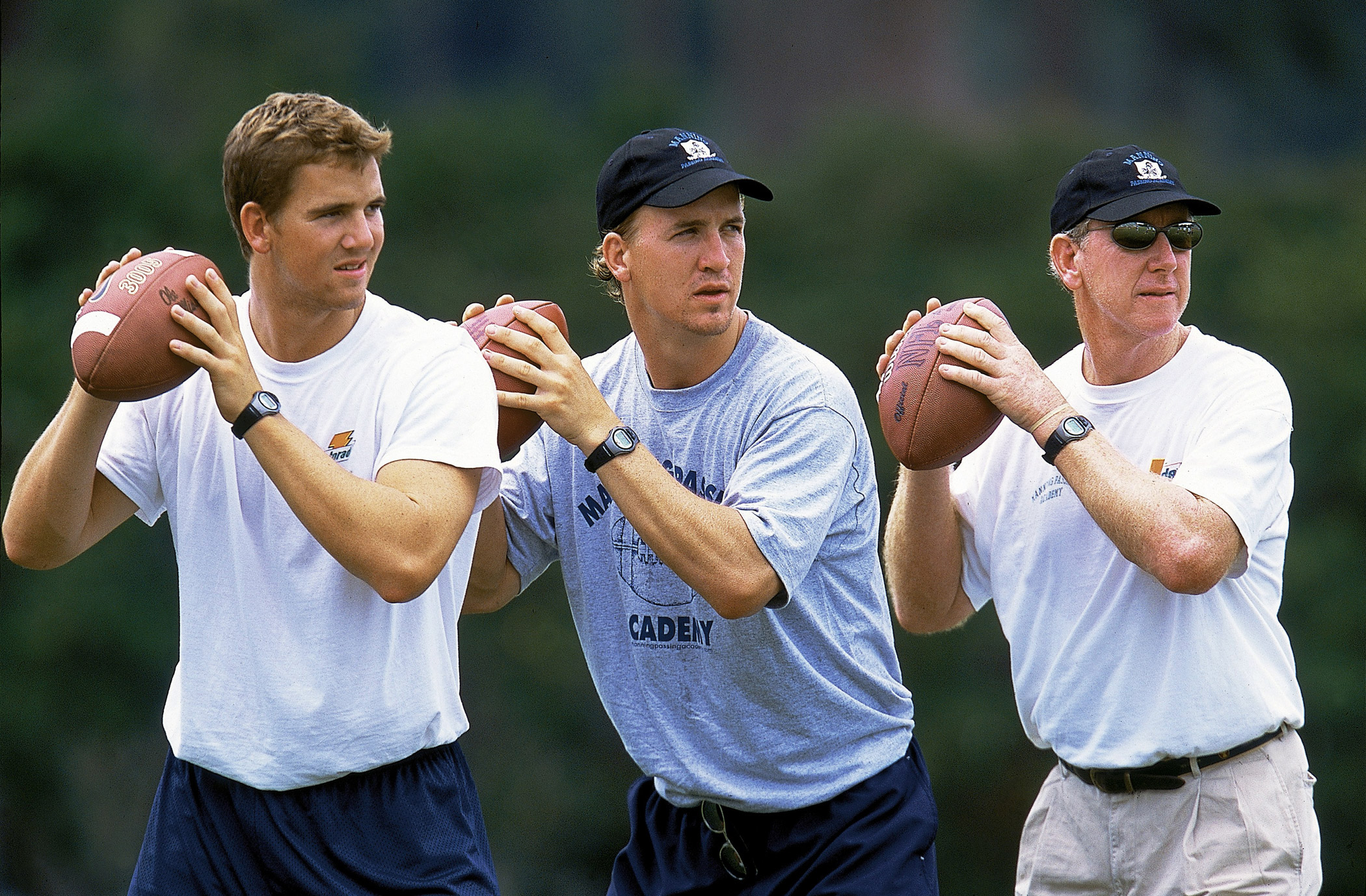 From left, Mississippi quarterback Eli Manning, Indianapolis Colts quarterback Peyton Manning, and former New Orleans Saints quarterback Archie Manning run a practice drill for high school quarterbacks at the Manning Passing Academy in  Hammond, La. in 2002.