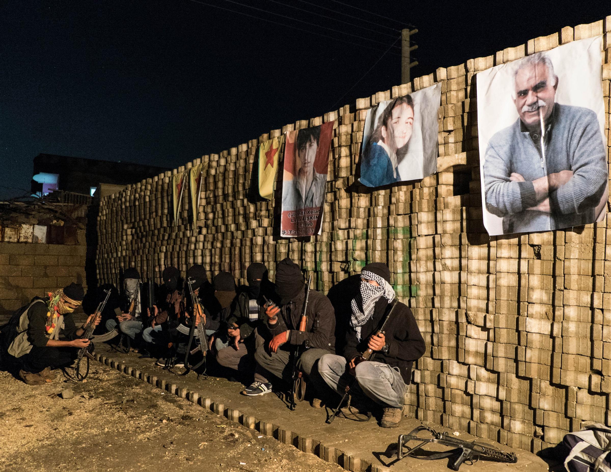 IDIL, TURKEY - OCTOBER 30, 2015: Kurdish youth militia YPS (Defense Forces of Civilians) hold their position behind a barricade and surveil an entrance to the Turgut Ozal autonomous neighborhood of Idil, a town in the Sirnak province. Several neighborhoods in Idil have declared autonomy and built self-rules, with groups of young Kurds who have taken up arms and raise barricades to prevent the advances of the Turkish forces.