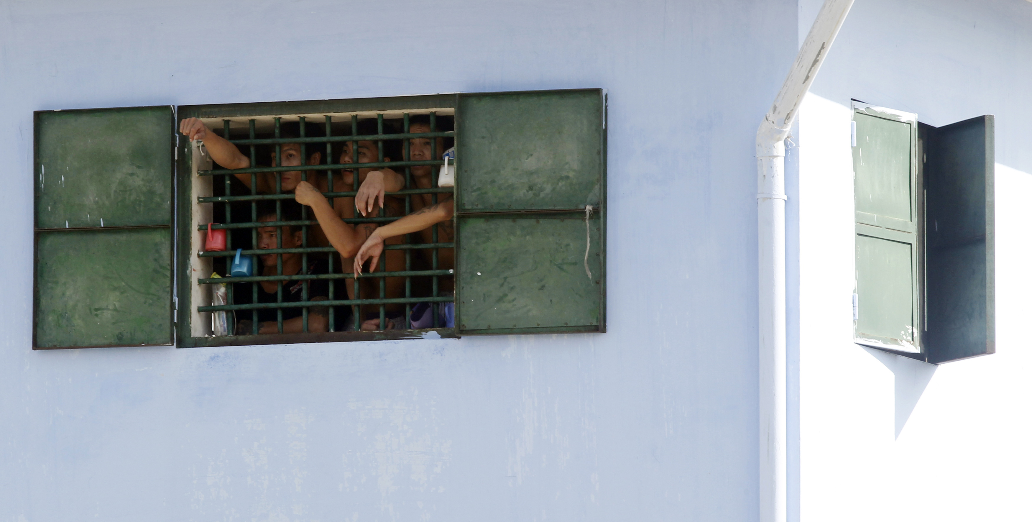Inmates look on from behind a barred window of a cell as they wave to released inmates at Hoang Tien prison outside Hanoi on Aug. 30, 2013 (Nguyen Huy Kham—Reuters)