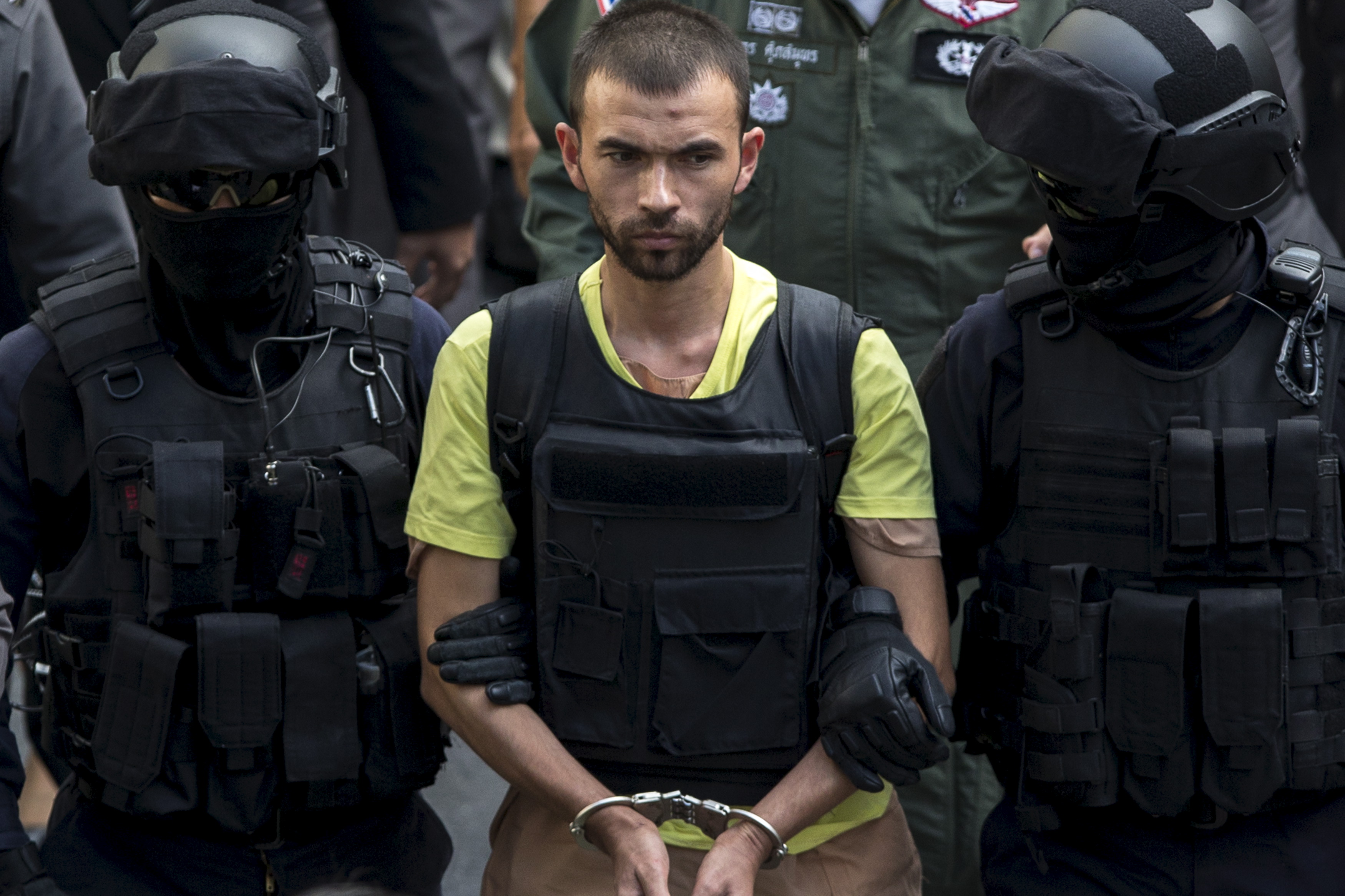 A suspect of the August 17 Bangkok blast is escorted by police officers during a crime re-enactment near the bomb site at Erawan Shrine in Bangkok