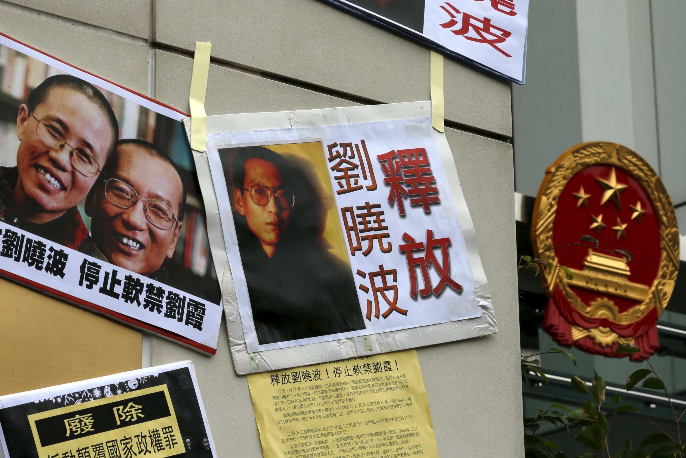 Signs and portraits of jailed Chinese Nobel Peace Prize laureate Liu Xiaobo and his wife Liu Xia are seen in front of the national emblem of China during a protest outside the Chinese liaison office in Hong Kong, China