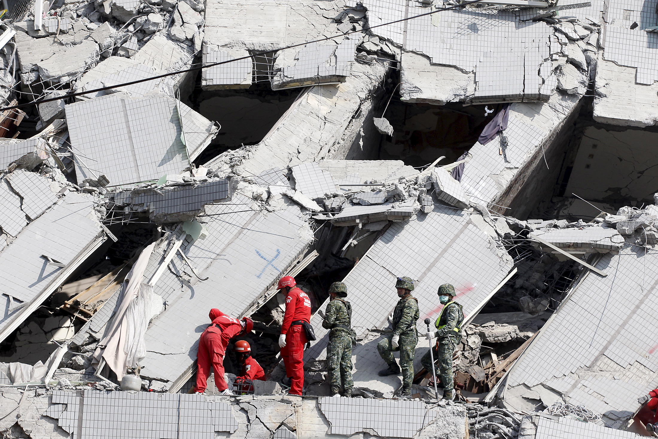 Rescue personnel work at the site where a 17 story apartment building collapsed from an earthquake in Tainan