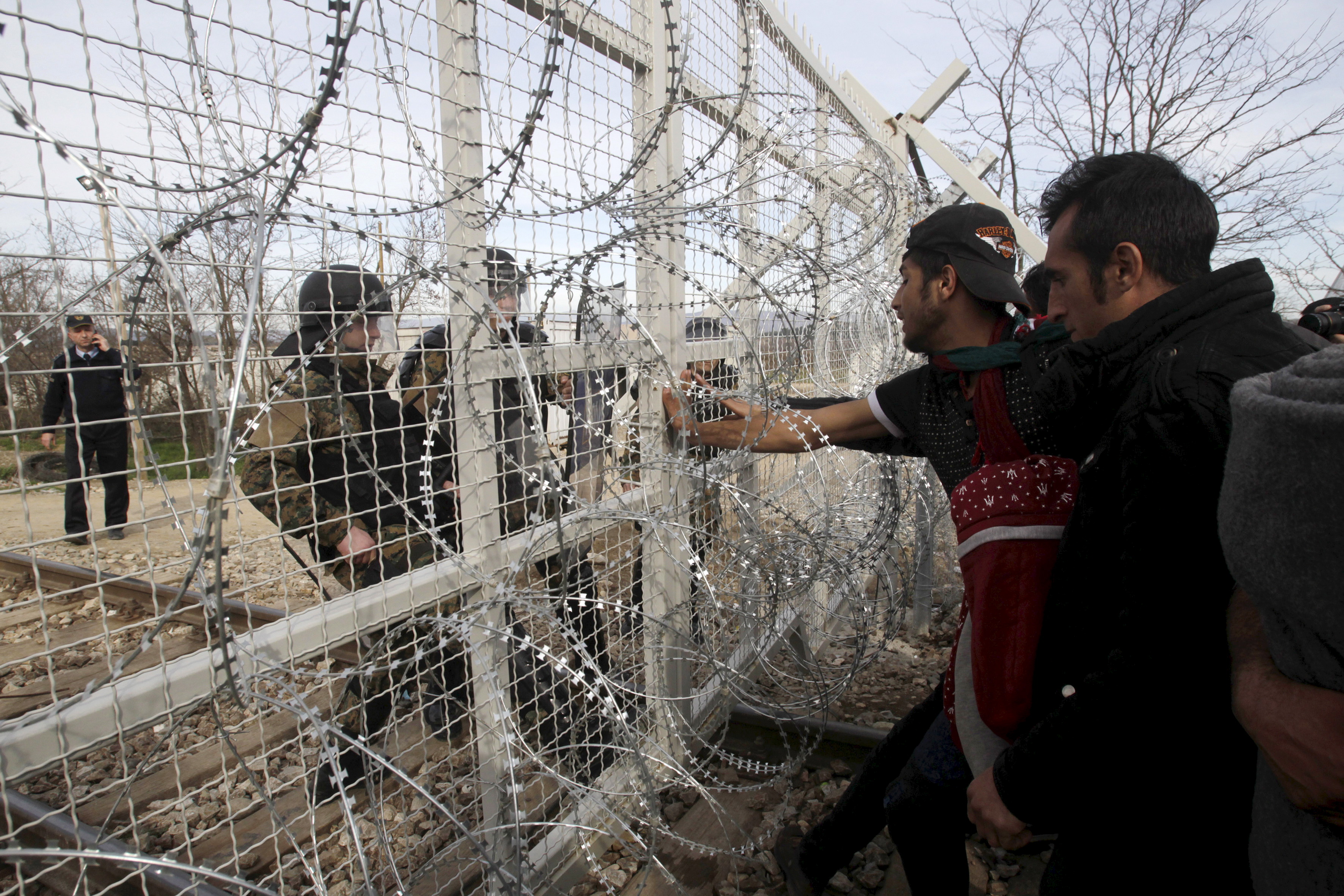 Refugees and migrants stand next to a border fence at the Greek-Macedonian border, near the village of Idomeni, Greece, on Feb. 22, 2016 (Alexandros Avramidis—Reuters)