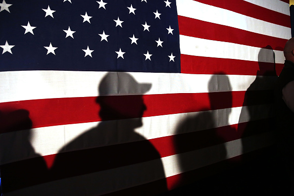 Shadows are reflected on an American Flag as people line up to speak with Ohio Governor and Republican presidential candidate John Kasich at a restaurant in South Carolina following his second place showing in the New Hampshire primary on February 11, 2016 in Myrtle Beach South Carolina.