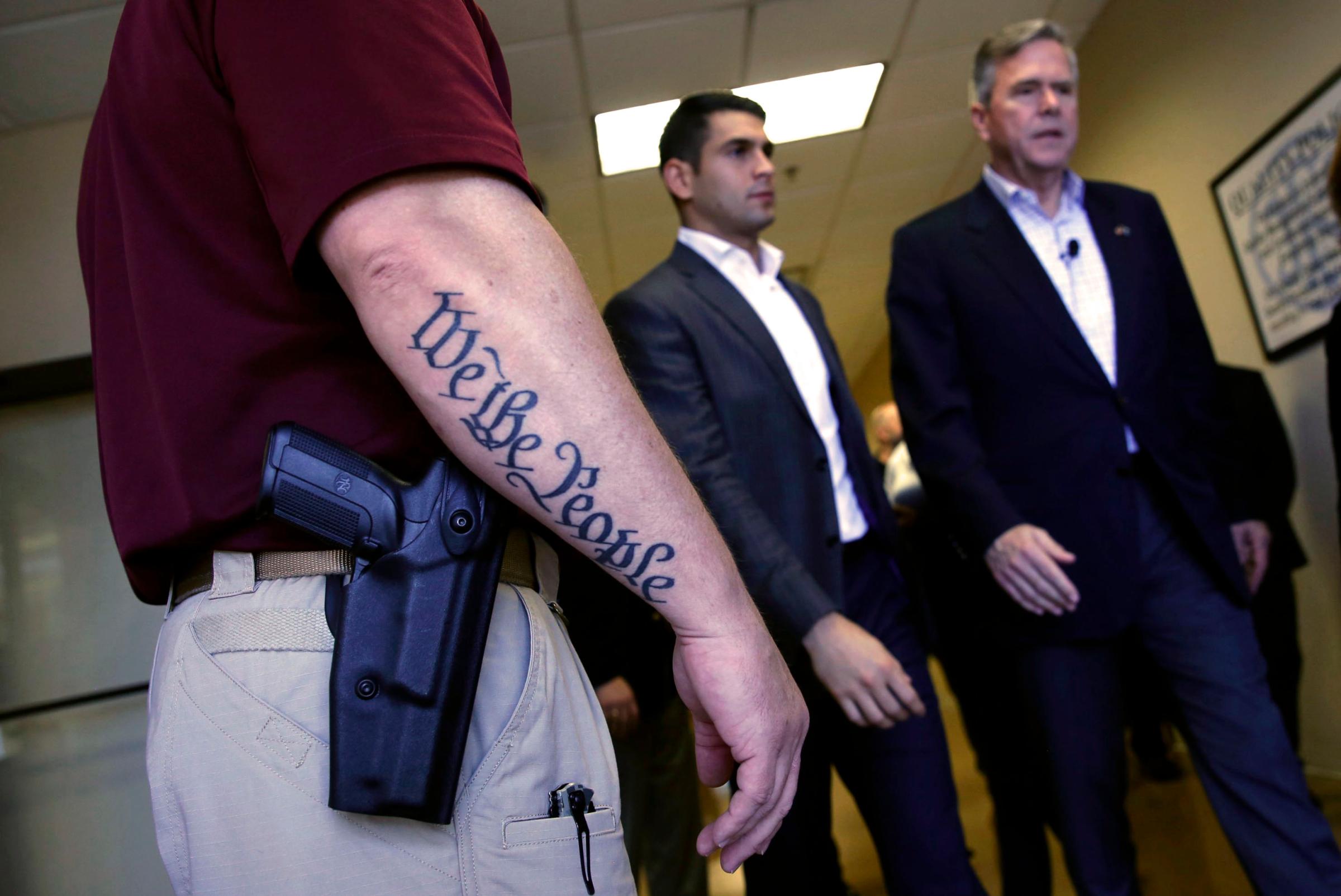 Republican presidential candidate Jeb Bush walks past a security guard after a town hall meeting with employees at FN America gun manufacturers in Columbia, S.C. on Feb. 16, 2016.