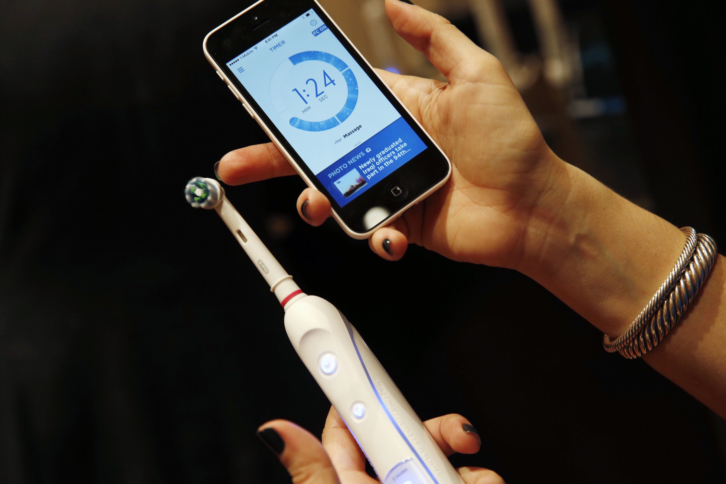 An attendee holds an Procter & Gamble Co. Oral-B SmartSeries electric toothbrush alongside an Apple Inc. iPhone during the 2015 Consumer Electronics Show (CES) in Las Vegas, Nevada, U.S., on Tuesday, Jan. 6, 2015.