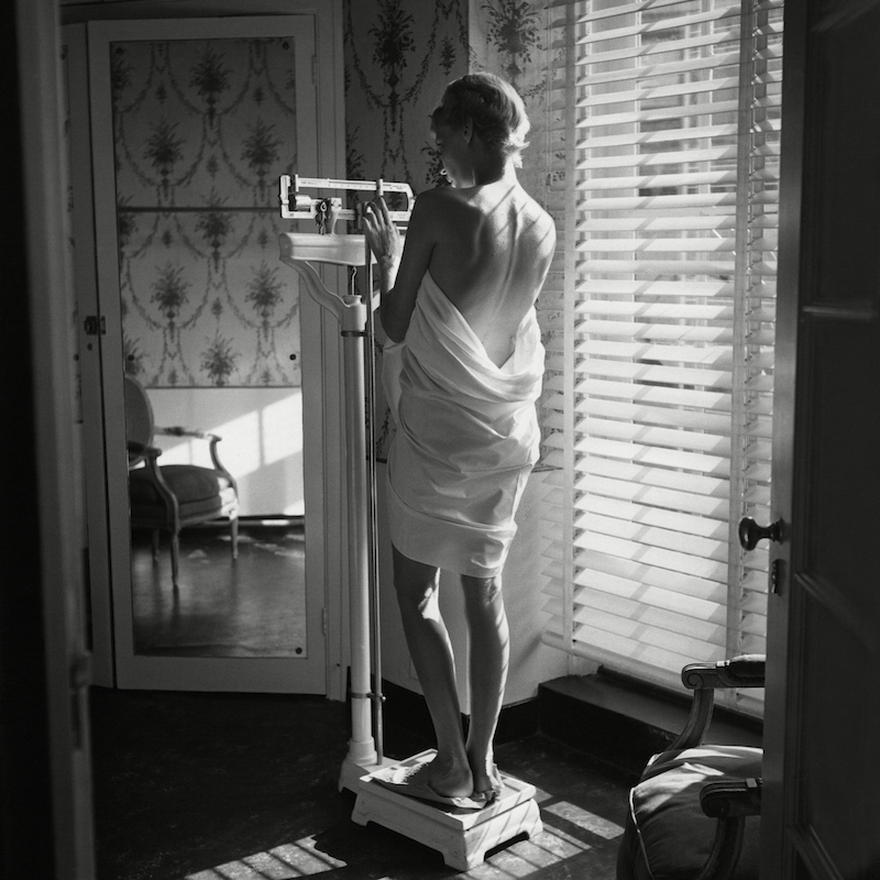 Woman weighing herself beside window in 1948 (Frances McLaughlin-Gill—The Condé Nast Publications/Getty Images)