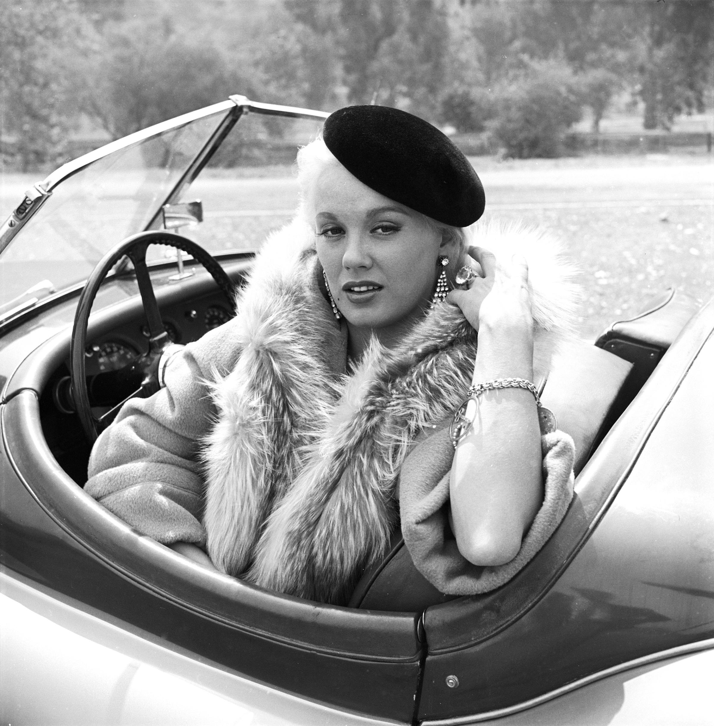 Mamie Van Doren sitting in her Jaguar wearing a hat. 1954.