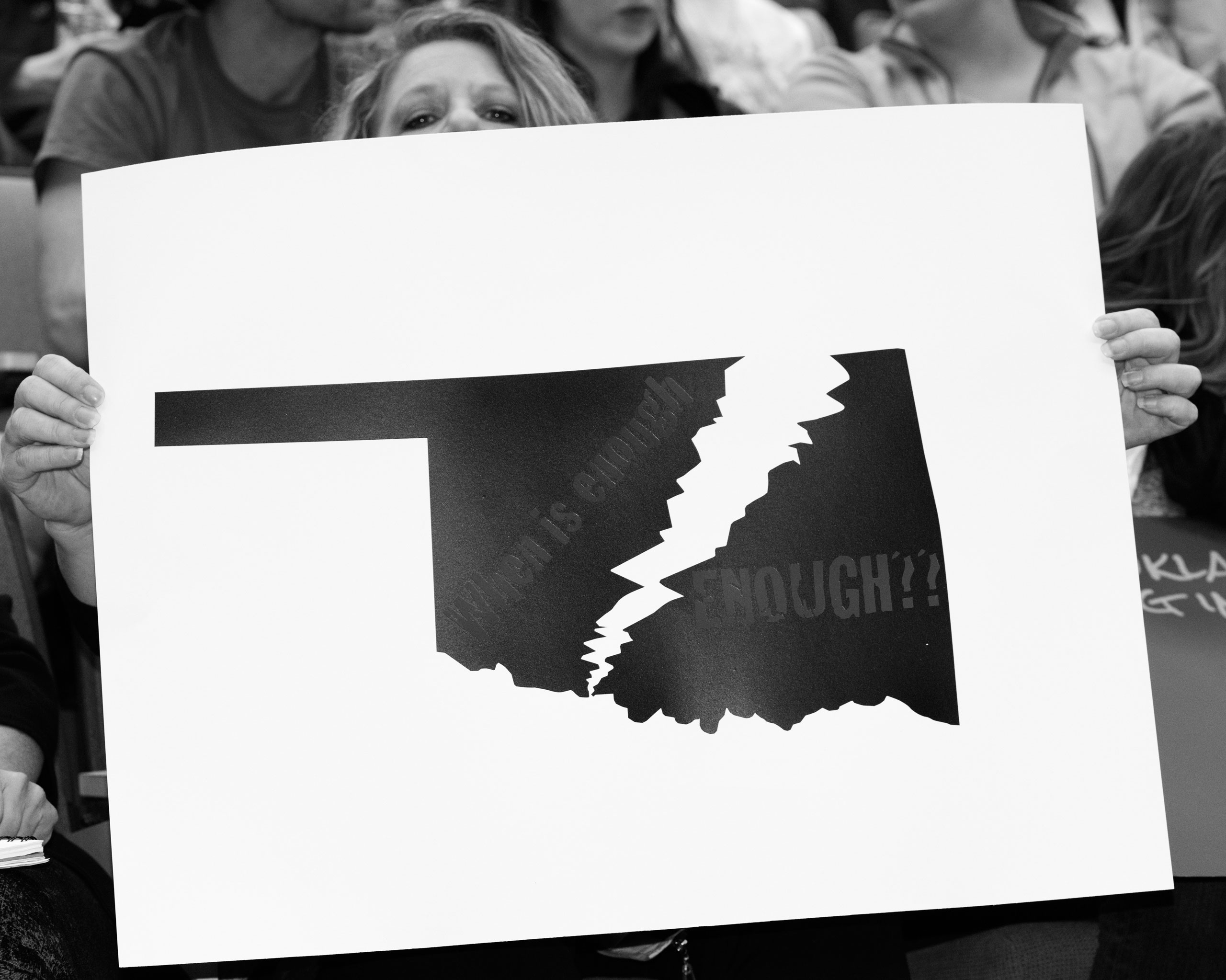 An attendee holds a protest sign at a public forum event hosted at the Univ. of Central Oklahoma, Edmond, OK