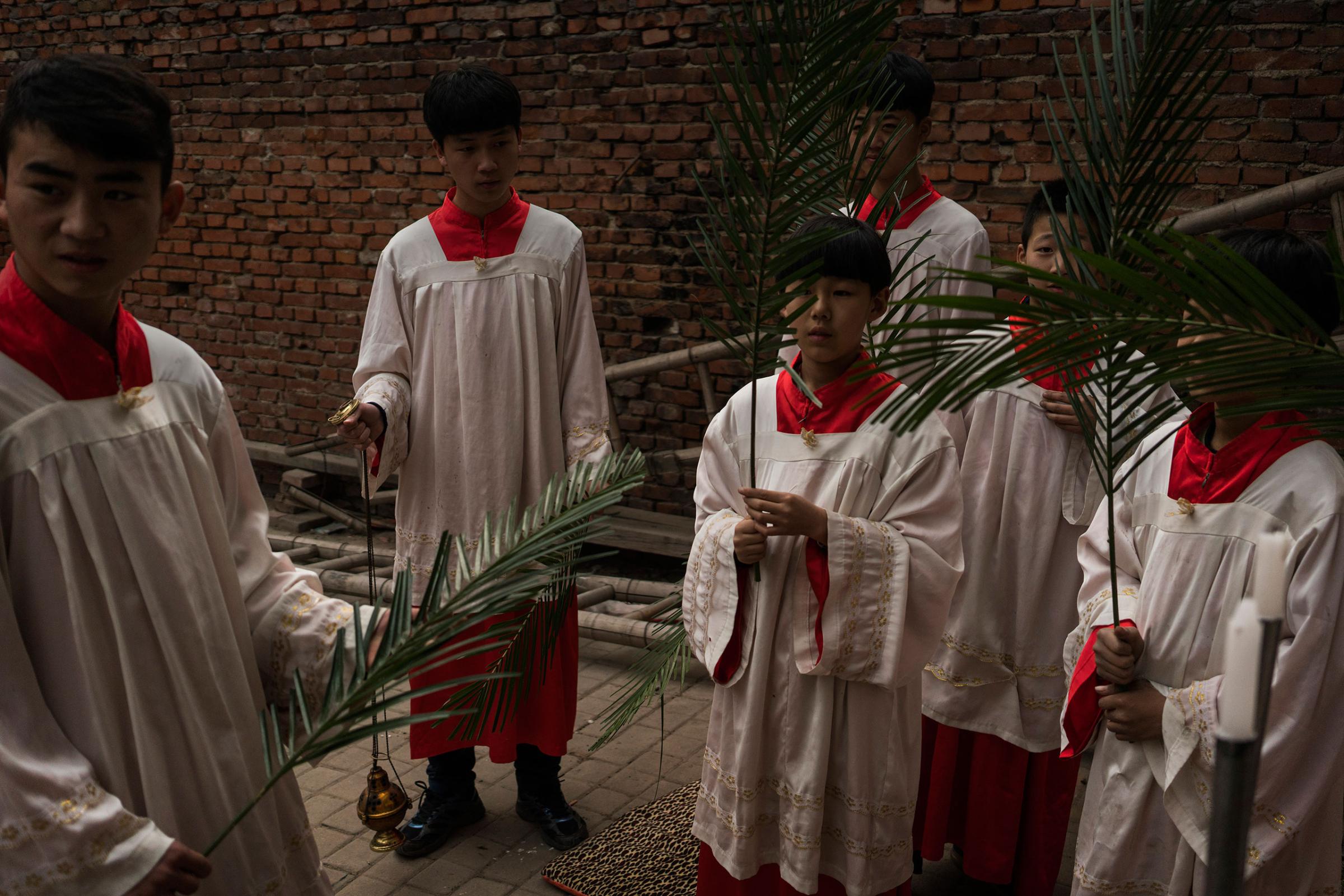 Altar boys prepare for an underground Palm Sunday service in the yard of a house in Youtong village, Shijiazhuang, China, March 20, 2016.