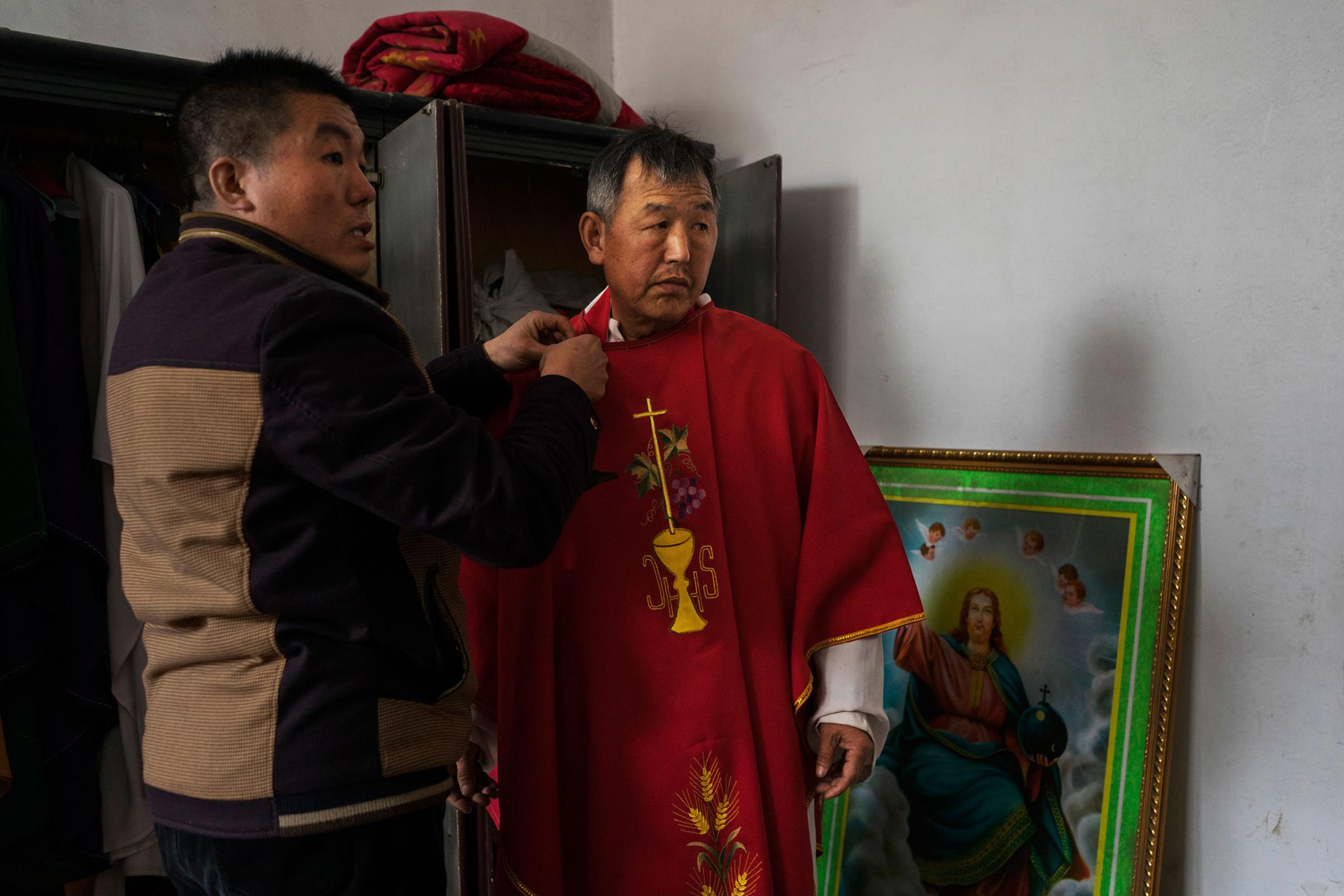 Dong Baolu, a dissident Catholic priest, is helped to dress ahead of a Palm Sunday service at an underground church service in the yard of a house in Youtong village, Shijiazhuang, China, March 20, 2016.