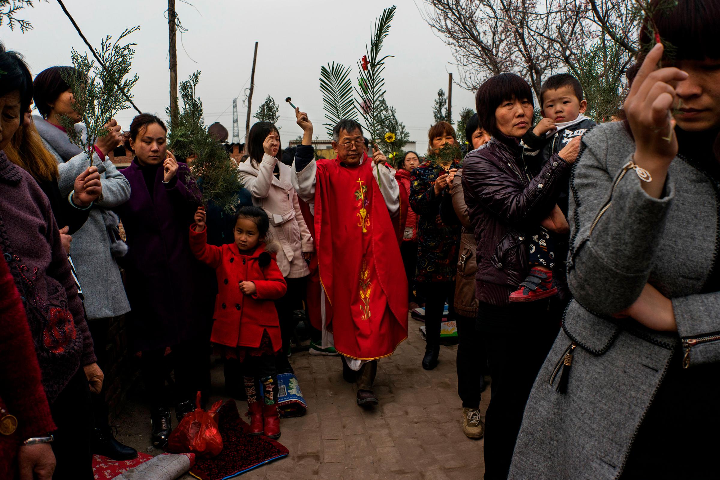 Dissident Catholic Priest Dong Baolu leads a procession through the congregation at an underground Palm Sunday service in the yard of a house in Youtong village, Shijiazhuang, China, March 20, 2016.