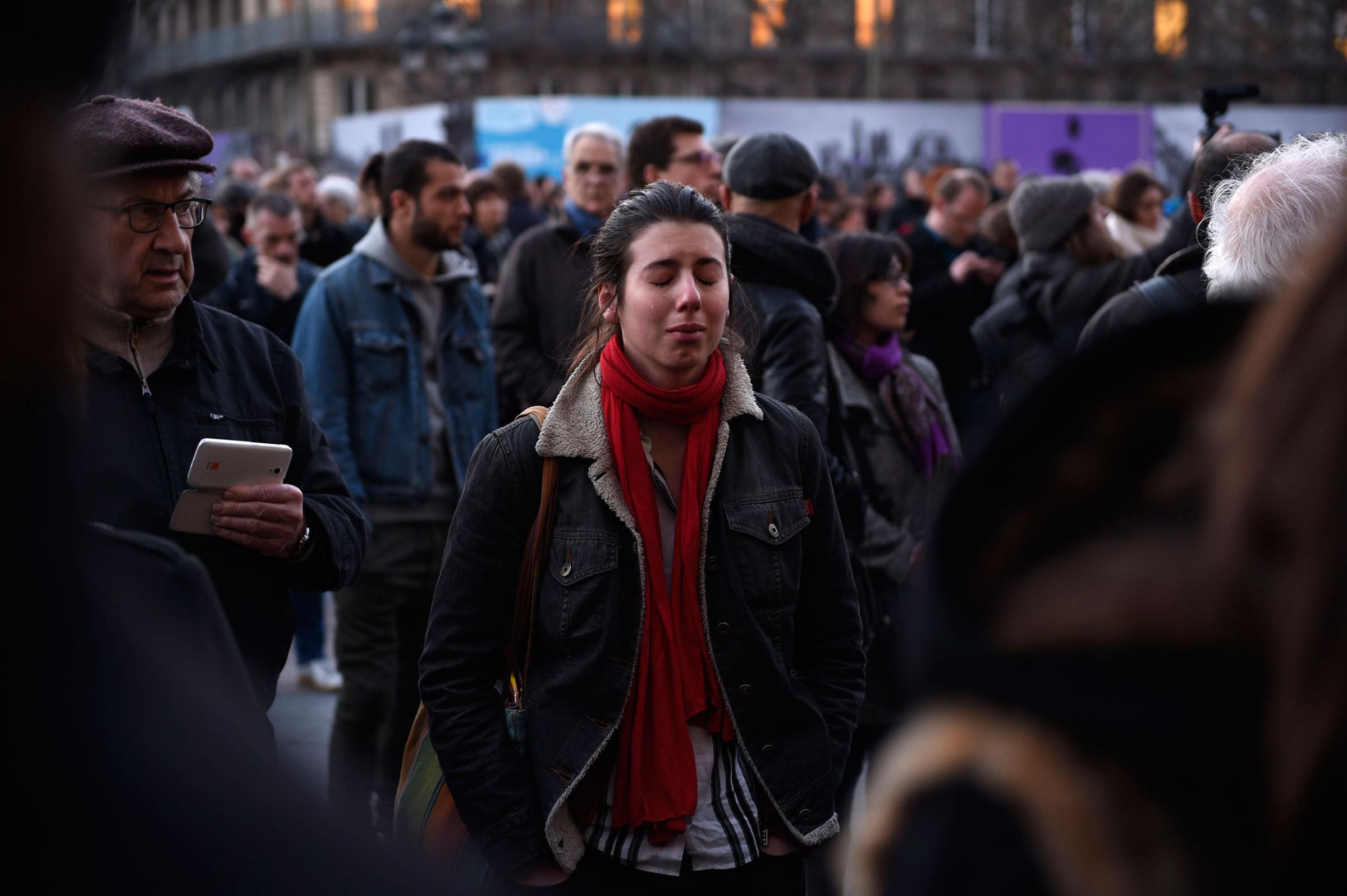 A woman mourning the victims of the Brussels terrorist attacks cries in front of the the city hall of Paris where people gather as a tribute, March 22, 2016.