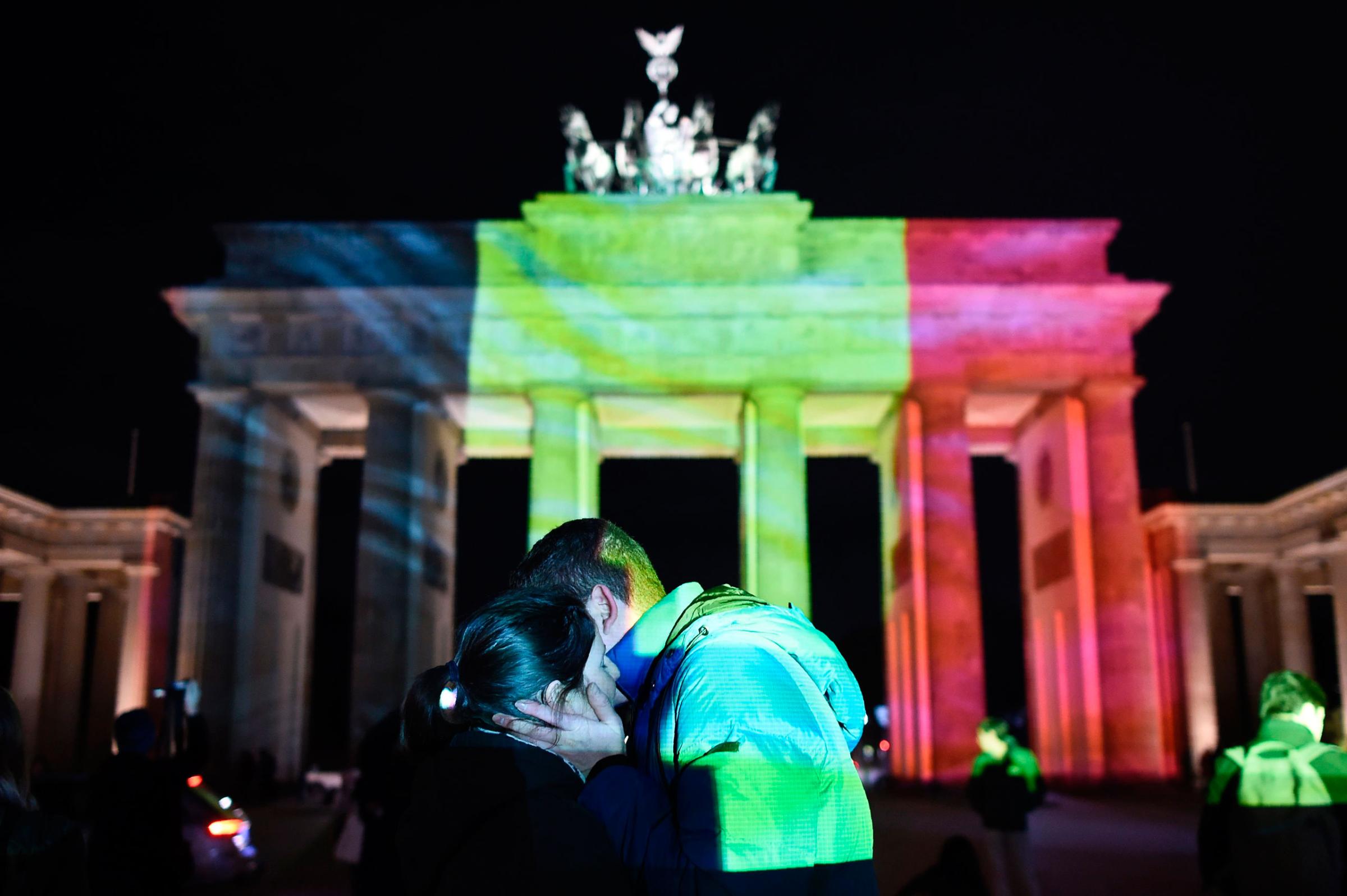 A couple embraces as the colors of the Belgian flag are projected on to the Brandenburg Gate in Berlin, March 22, 2016.