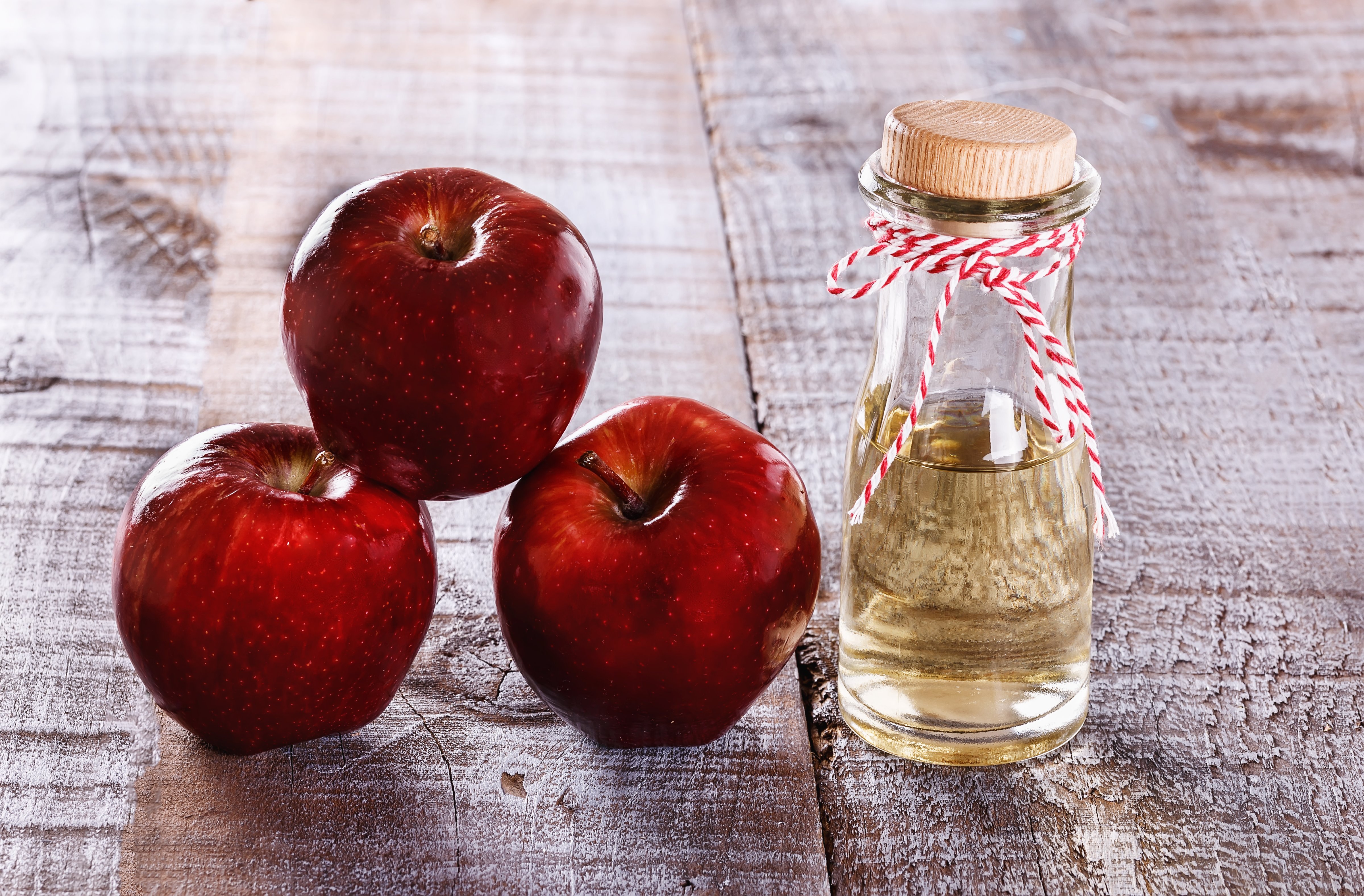 Apple cider vinegar and apples over white wooden background (Getty Images)