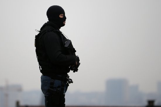 A member of the special police forces stands guard outside the Council Chamber of Brussels during investigations into the Paris and Brussels terror attacks on March 24, 2016.