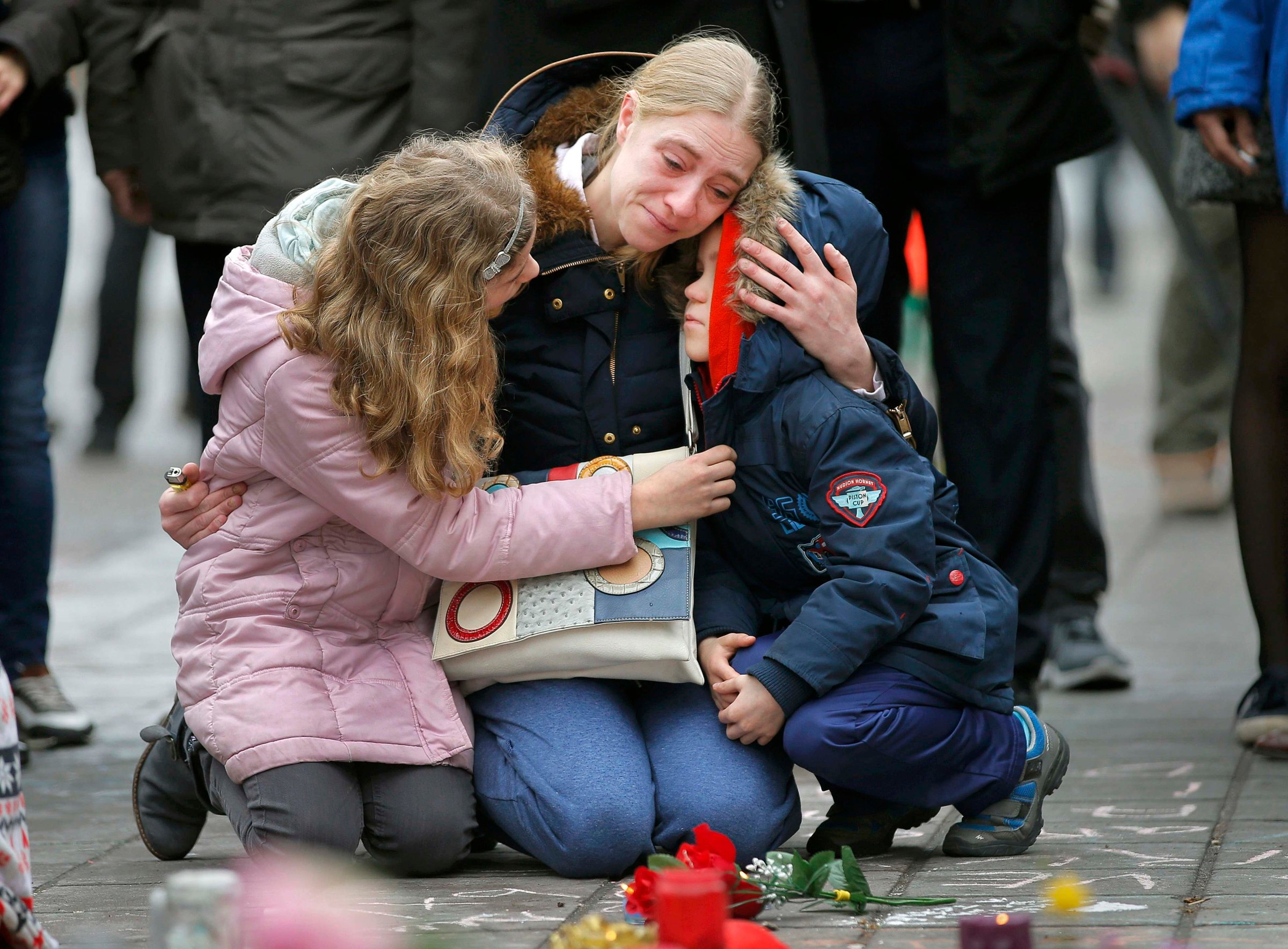 A woman consoles her children at a street memorial following bomb attacks in Brussels, Belgium