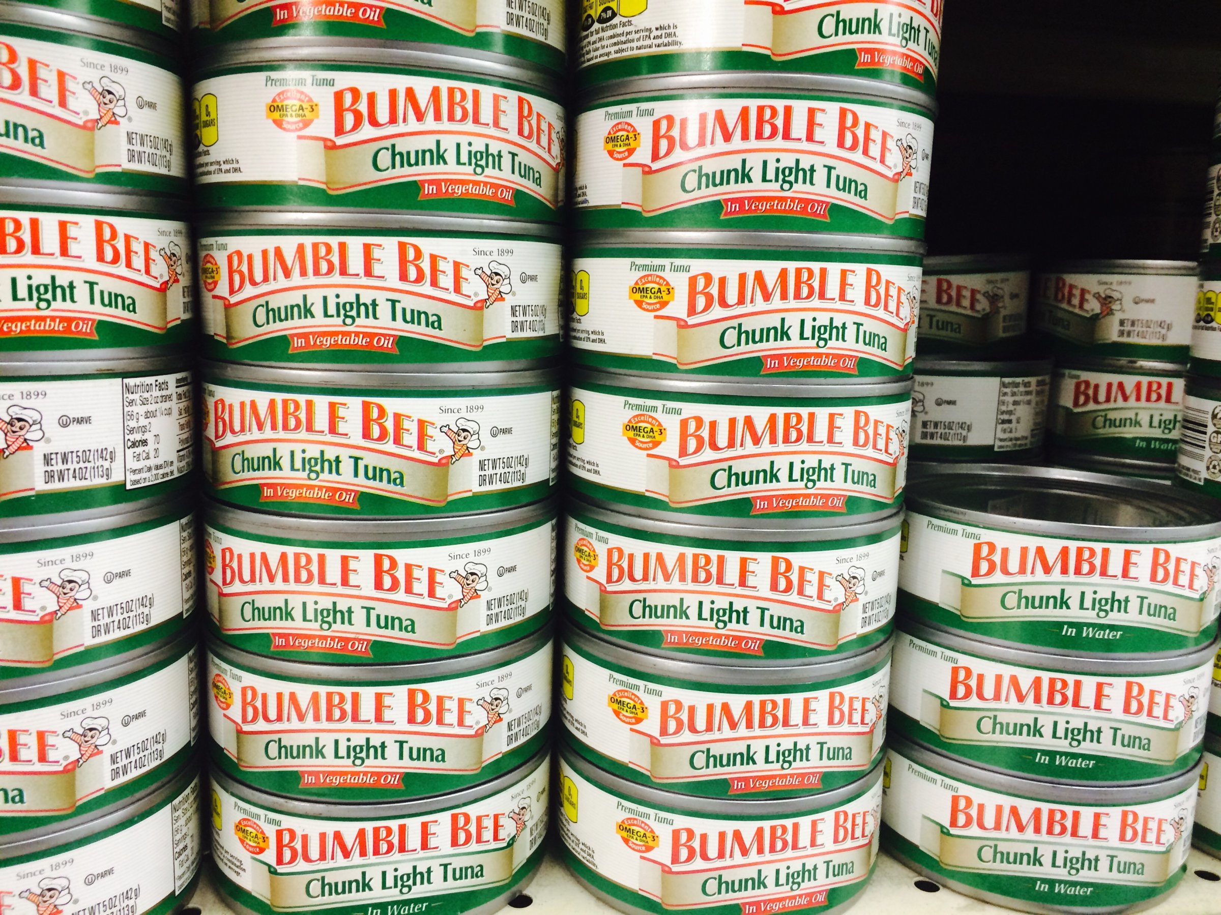 Bumble Bee chunk light tuna can is seen on a shelf at a grocery store.