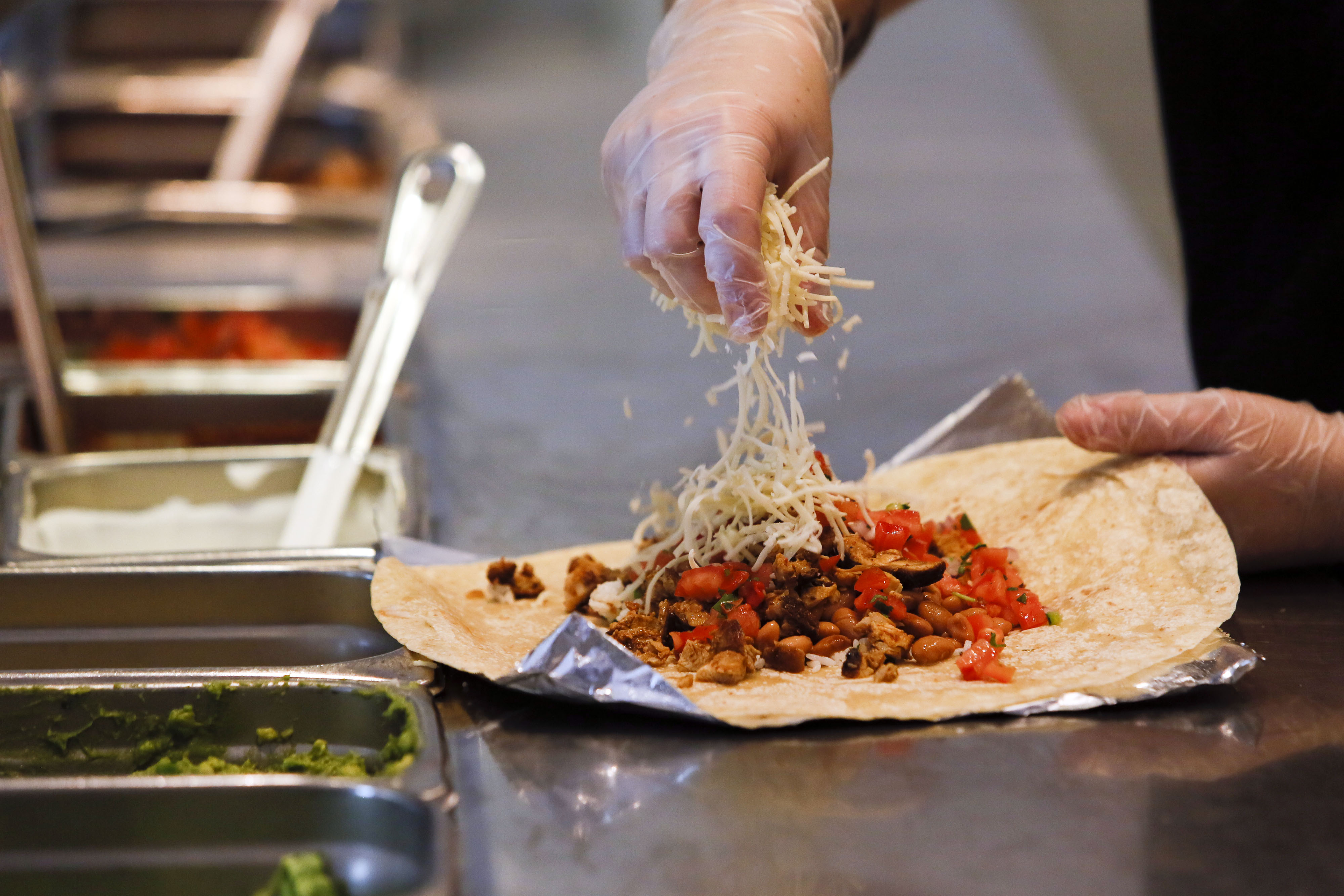 A employee sprinkles cheese on a burrito at a Chipotle restaurant in Hollywood, on July 16, 2013. (Patrick T. Fallon—Bloomberg/Getty Images)