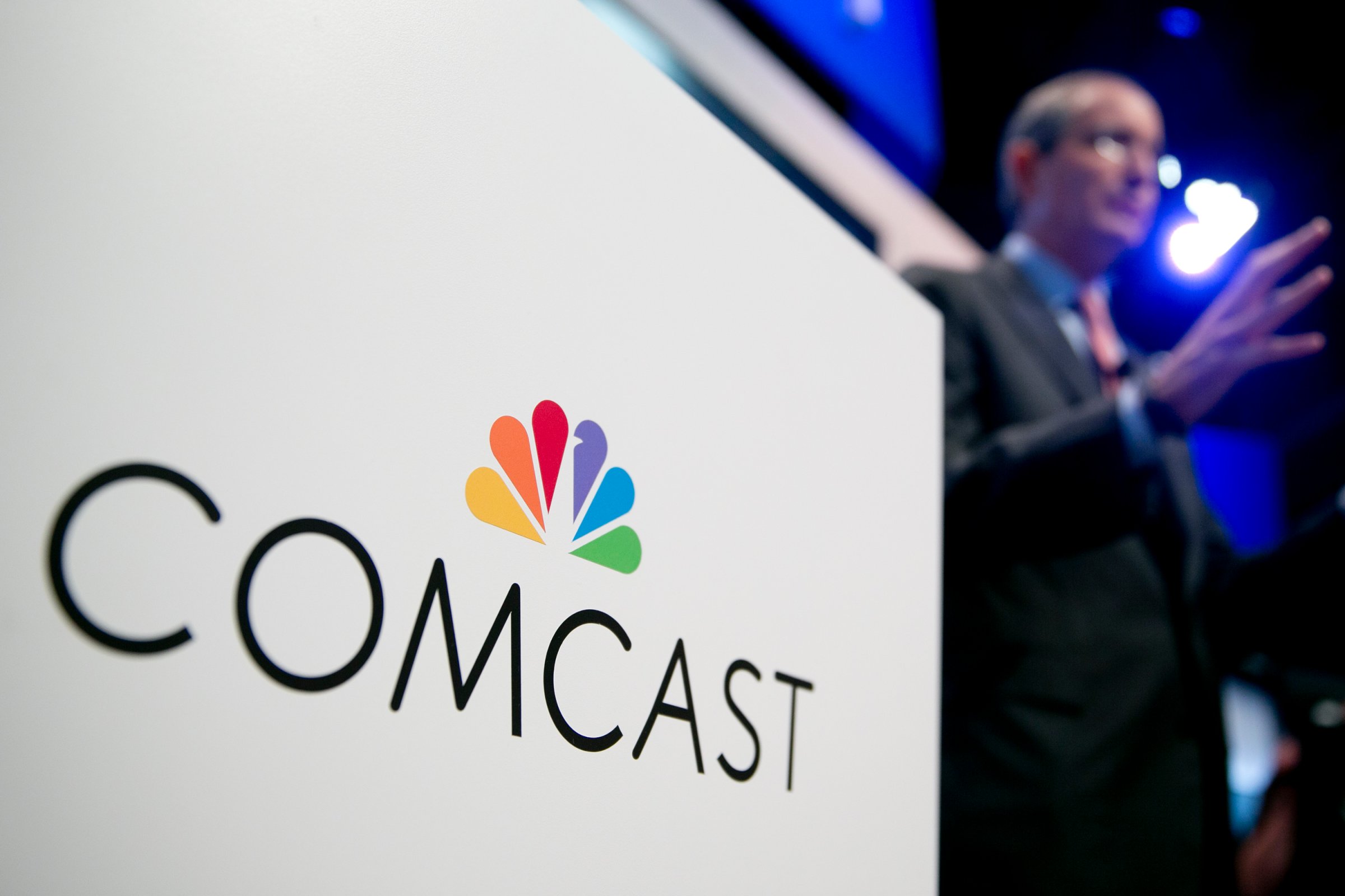 The Comcast Corp. logo is seen as Brian Roberts, chairman and chief executive officer of Comcast Corp., right, speaks during a news conference at the National Cable and Telecommunications Association (NCTA) Cable Show in Washington, D.C., U.S., on Tuesday, June 11, 2013.