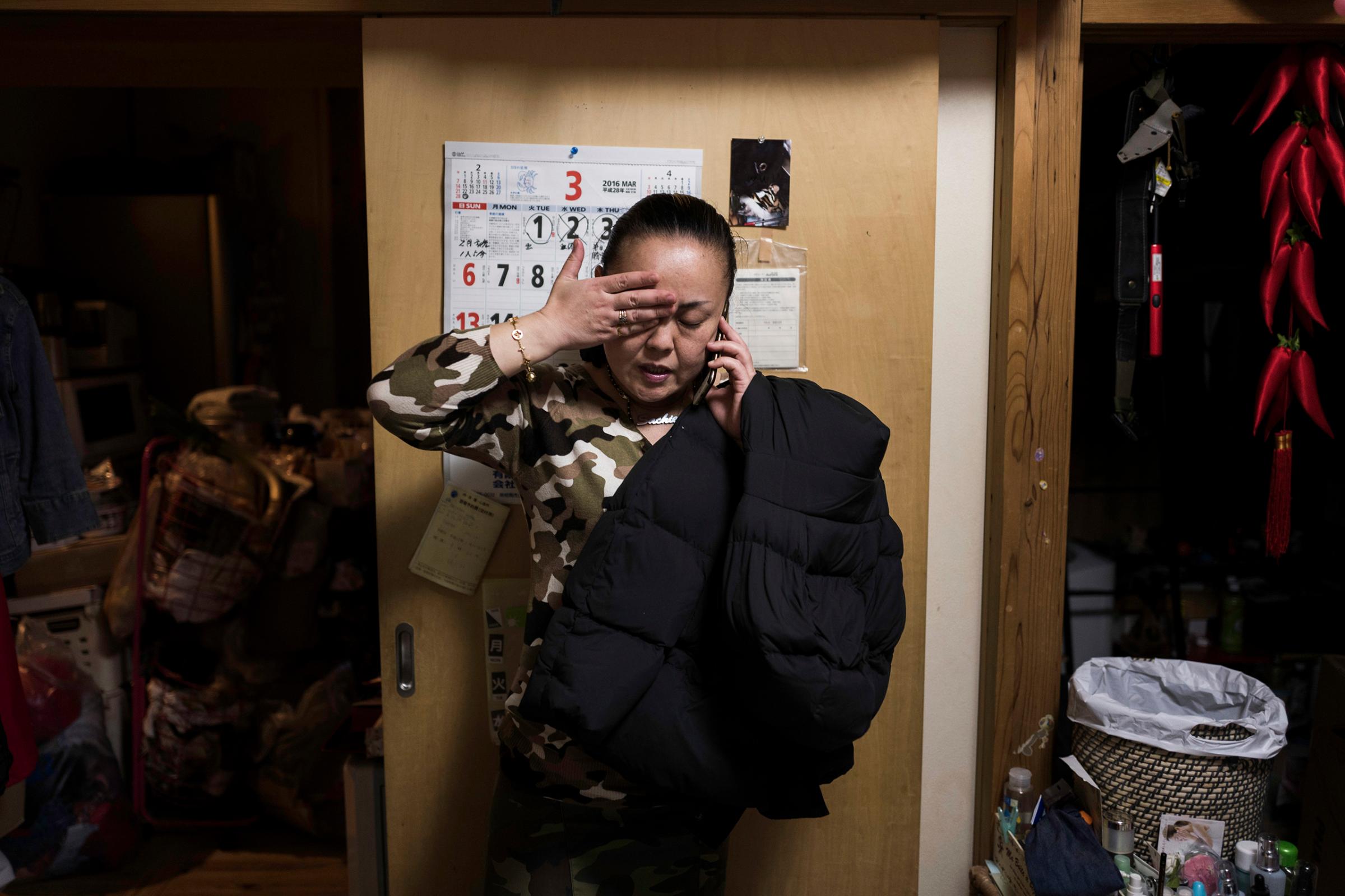 Sachie Matsumoto talks on the phone inside her temporary house in Minamisoma, Fukushima, March 3, 2016. Her son, a decontamination worker, tried to commit suicide. Her family will soon move to a new home built with savings and compensation money.