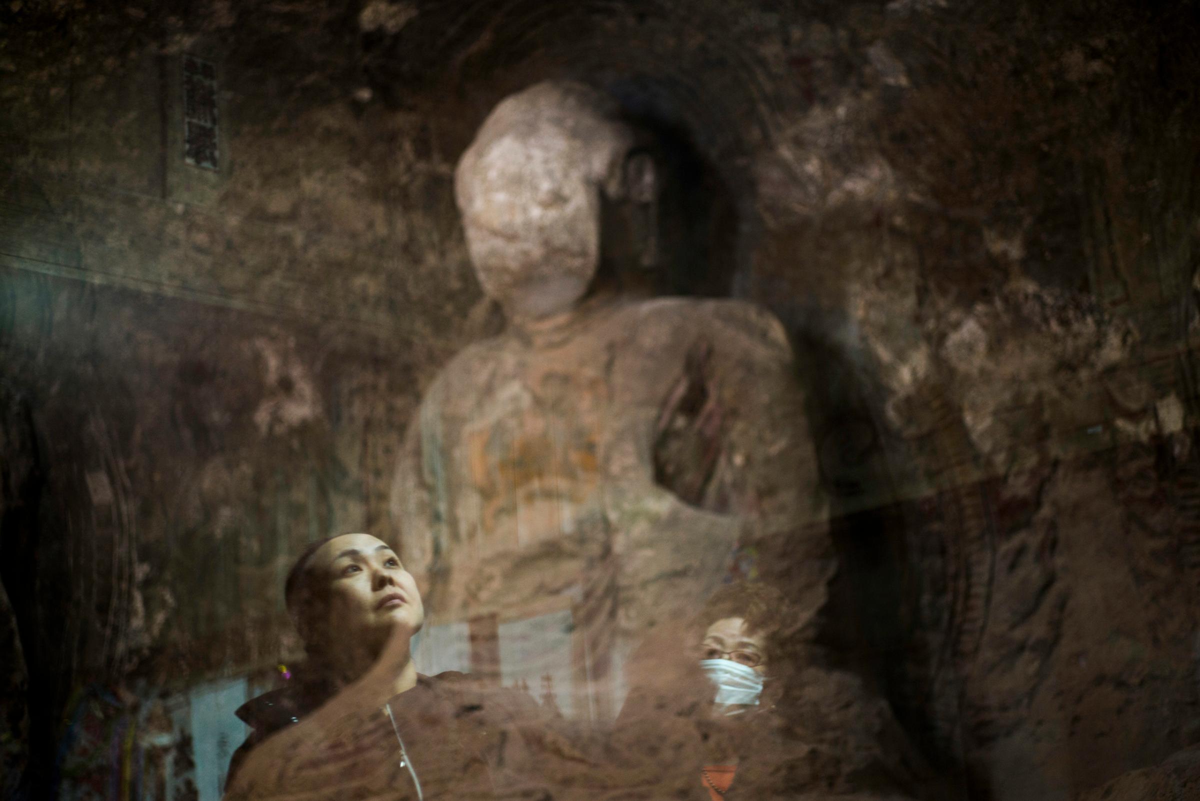 Sachie Matsumoto, 43, and her mother look up at a Buddha statue called “Daihisan no Sekibutsu,” or “Stone Buddha statue of mountain of great sadness,” carved more than 1,000 years ago and situated inside the 20km exclusion zone, Osaka, Japan, March 6, 2016. Sachie would come here as a child.