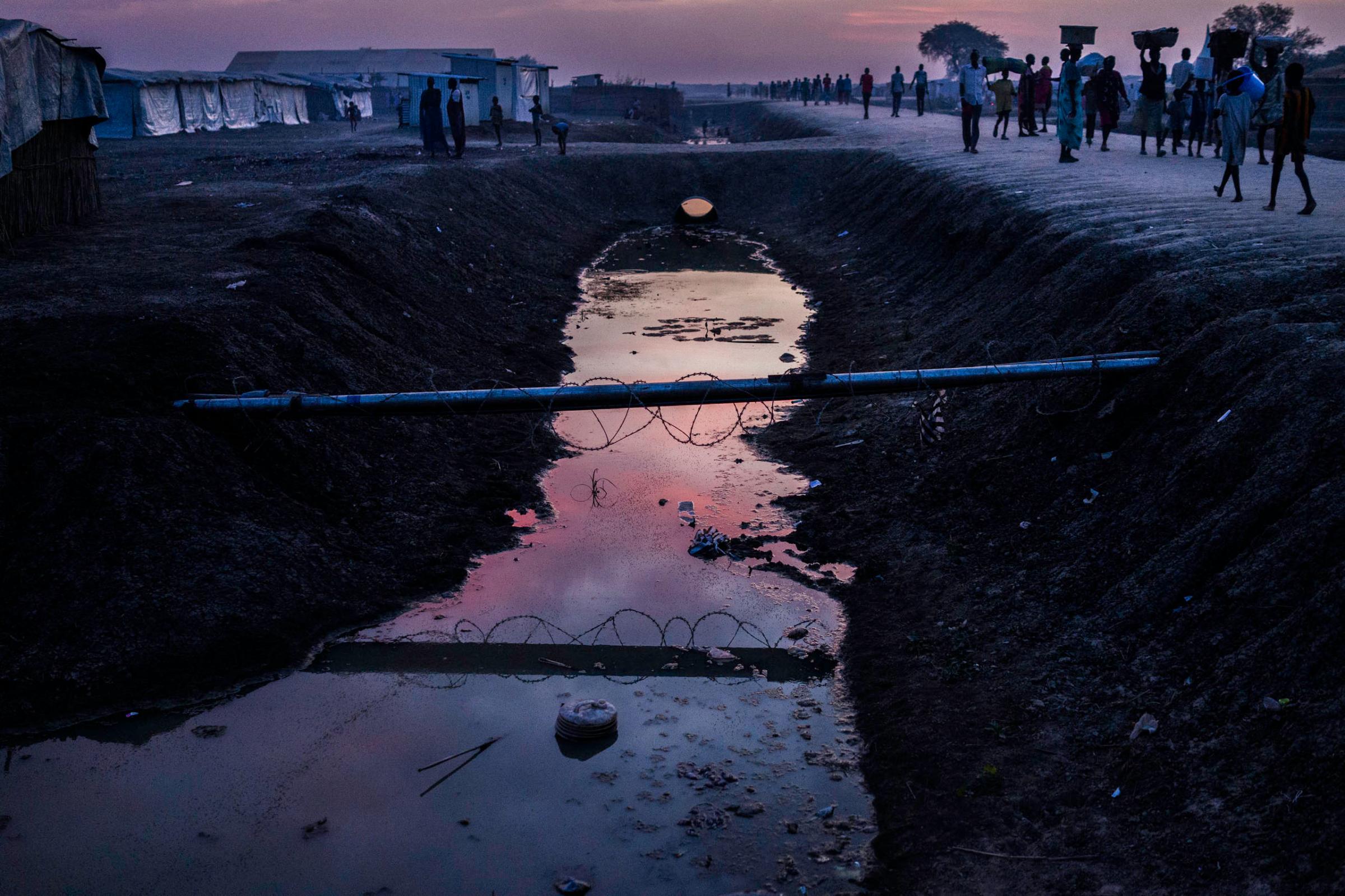 People walk past a drainage ditch in the United Nations camp in Bentiu, Unity State, South Sudan.