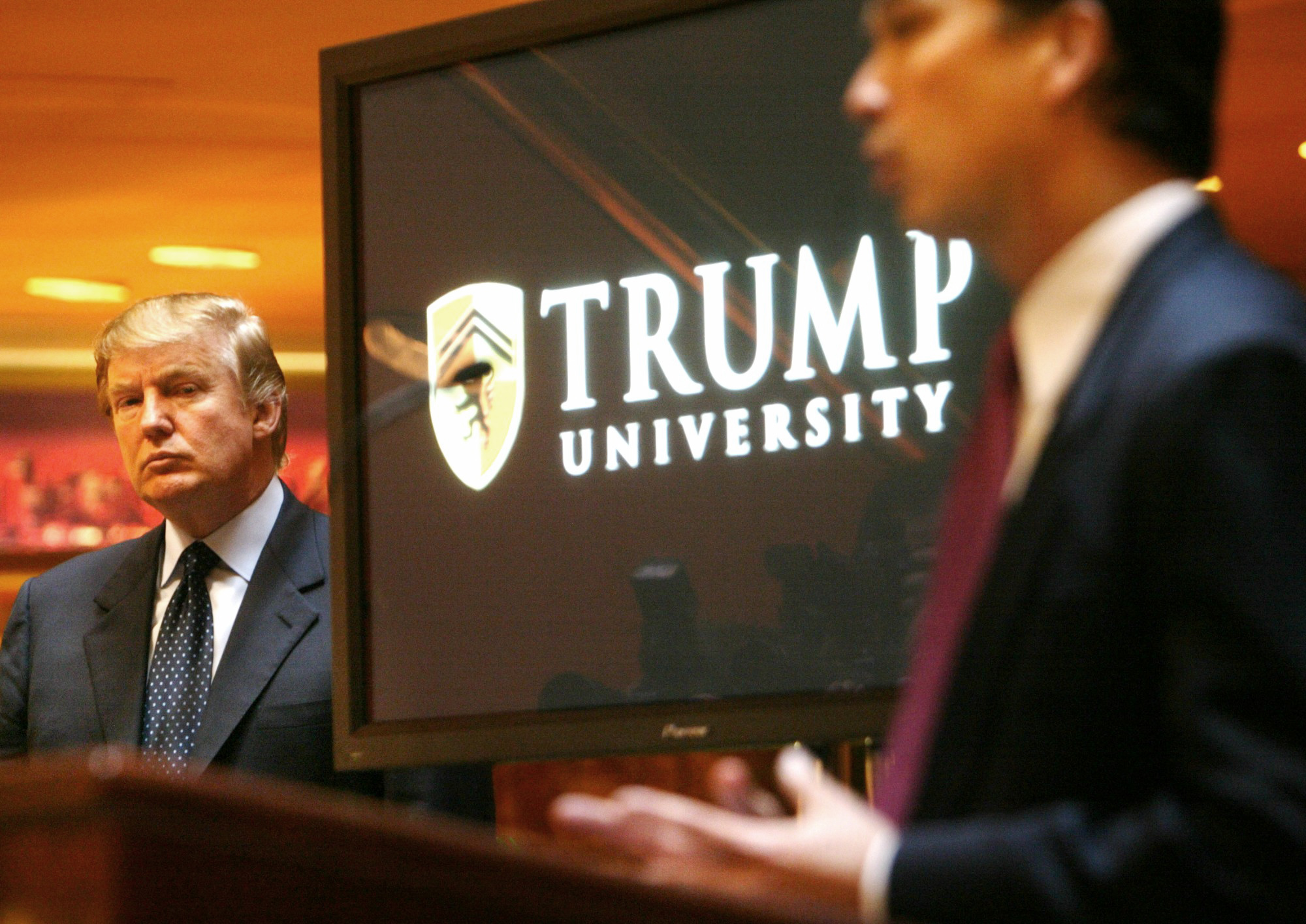 Donald Trump listens as Michael Sexton introduces him at a news conference in New York where he announced the establishment of Trump University on May 23, 2005.