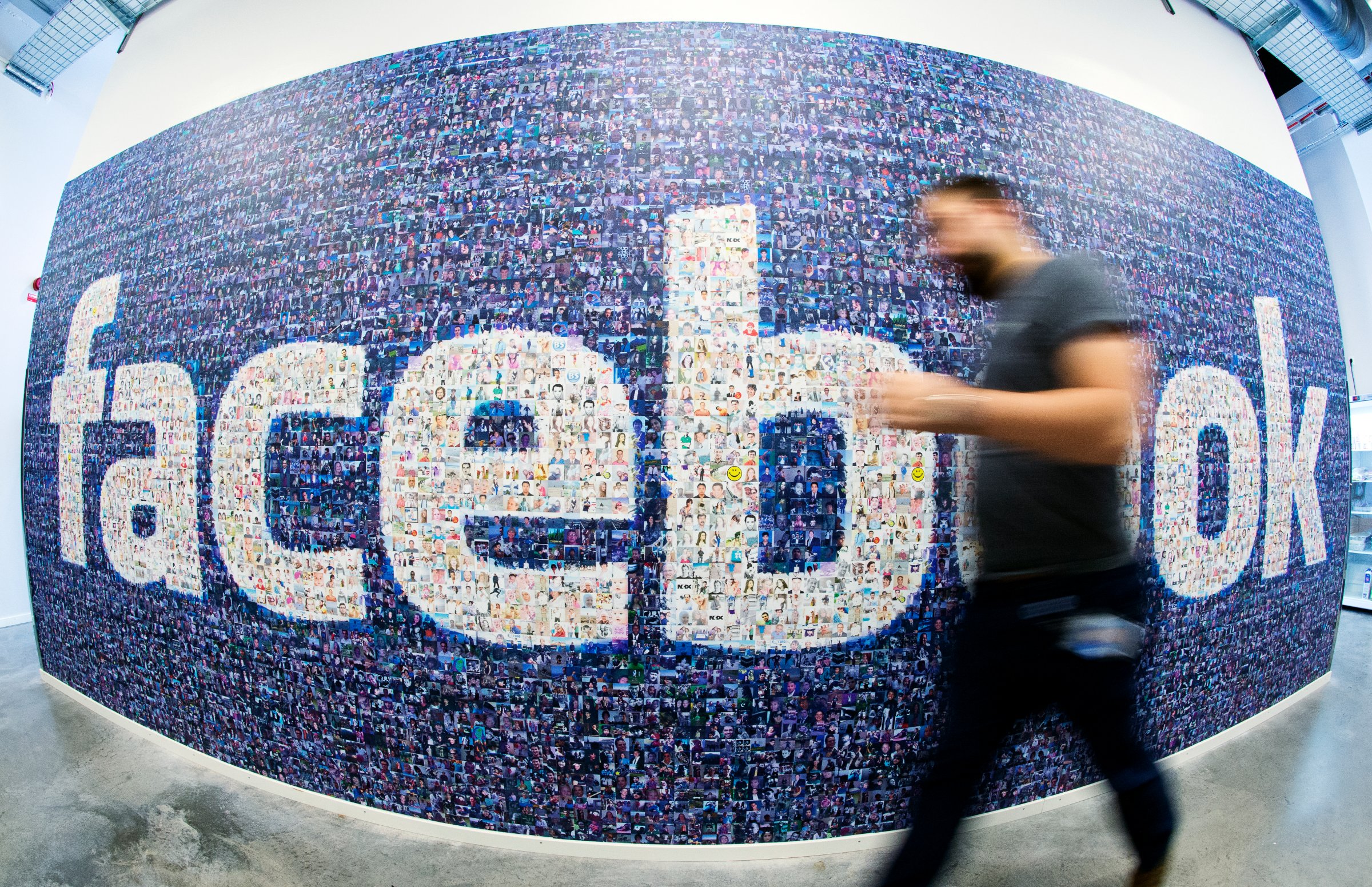 This picture taken with a fisheye lens shows a man walk past a big logo created from pictures of Facebook users worldwide in the company's Data Center, its first outside the US on November 7, 2013 in Lulea, in Swedish Lapland.