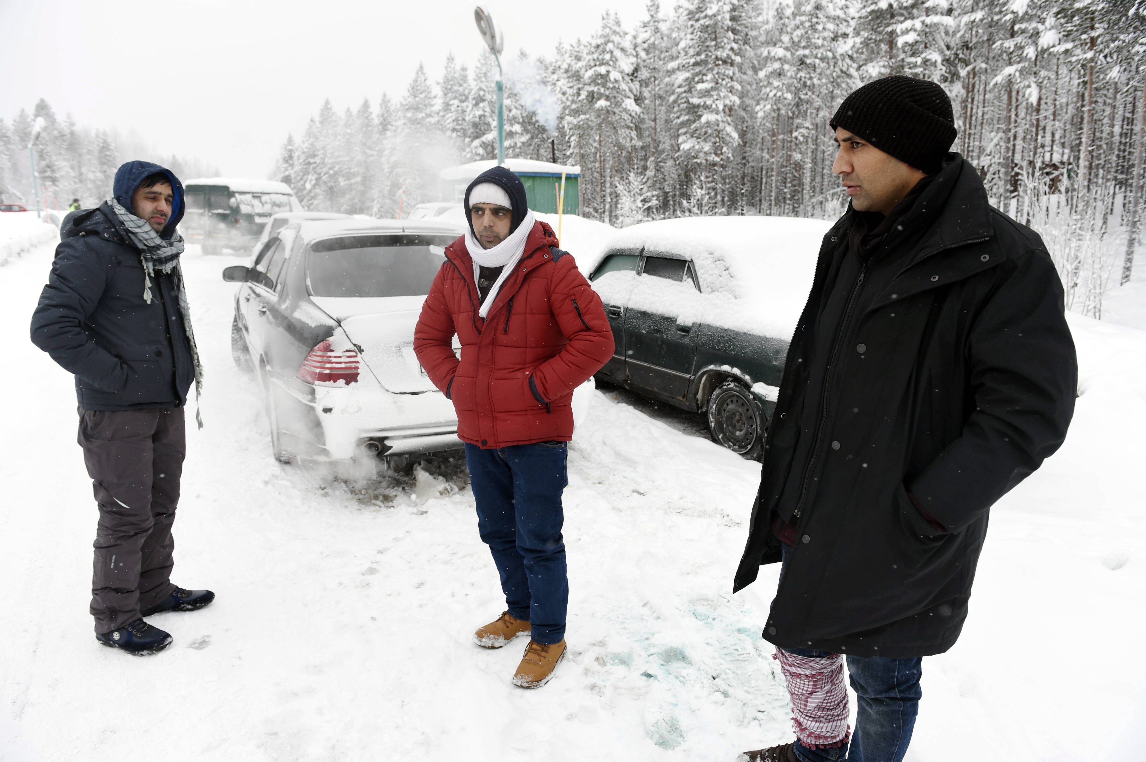 Asylum seekers Rahmatullah, left, and Nazirulhag, center, from Afghanistan and Fida Hussain from Pakistan wait on the Russian side of the border on Jan. 23, 2016 (Jussi Nukari—AFP/Getty Images)