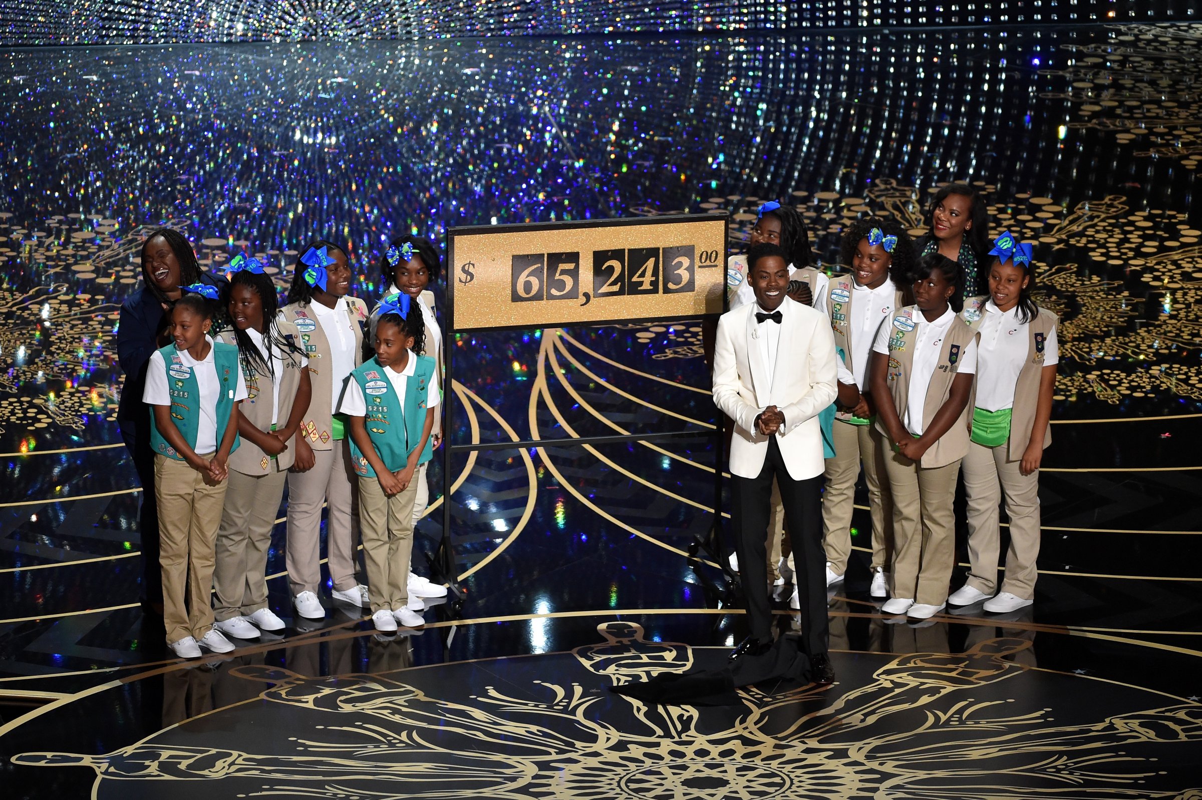 Host Chris Rock (C) presents the amount of money collected during the show by the Girl Scouts, including Rock's daughters Zahra and Lola, onstage at the 88th Annual Academy Awards at the Dolby Theatre on February 28, 2016 in Hollywood, California.